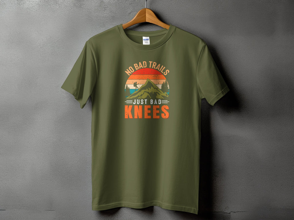 Olive green t-shirt with "No Bad Trails Just Bad Knees" mountain graphic.