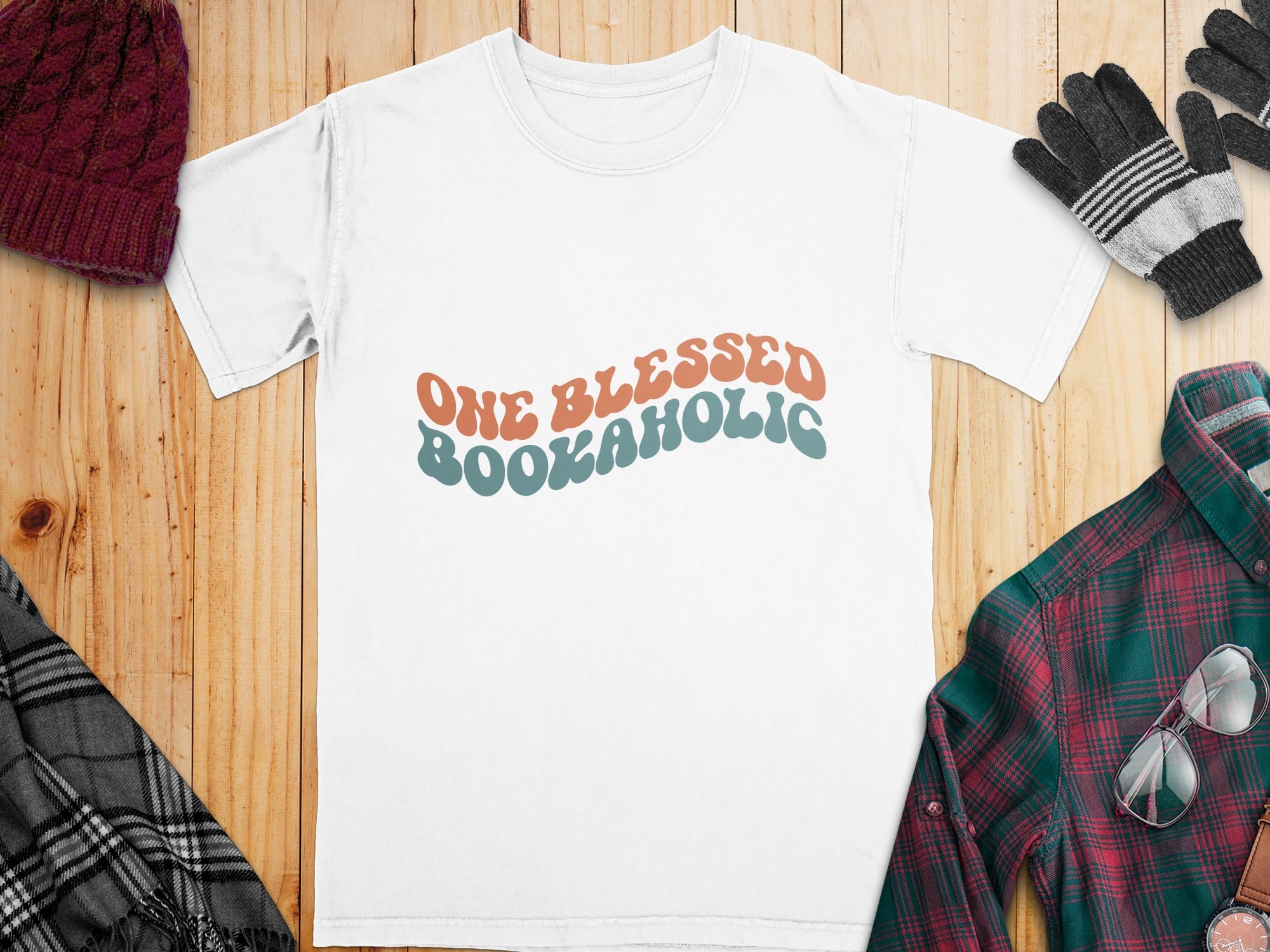 White t-shirt with "ONE BLESSED BOOKAHOLIC" text in retro wavy font.