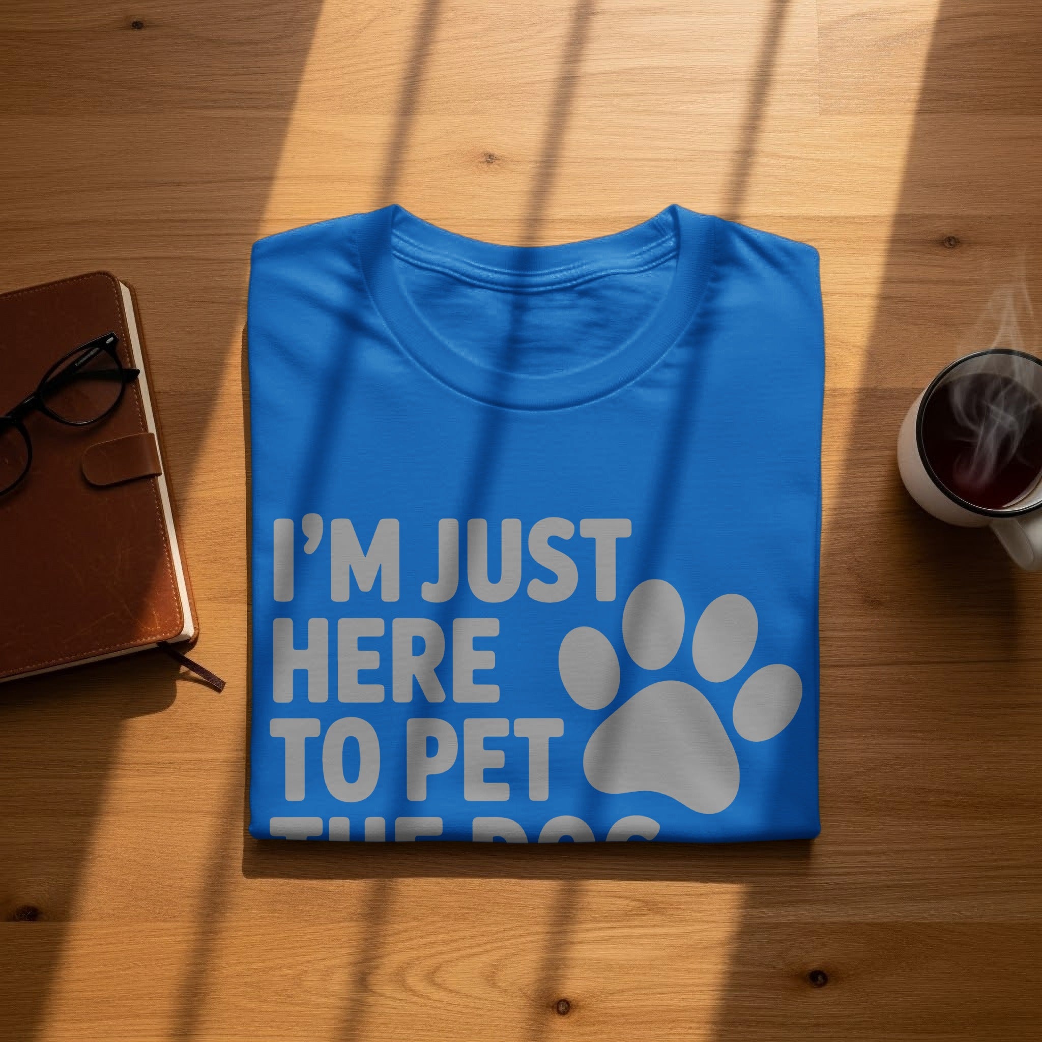 Blue t-shirt with "I'M JUST HERE TO PET THE DOG" text and paw print.
