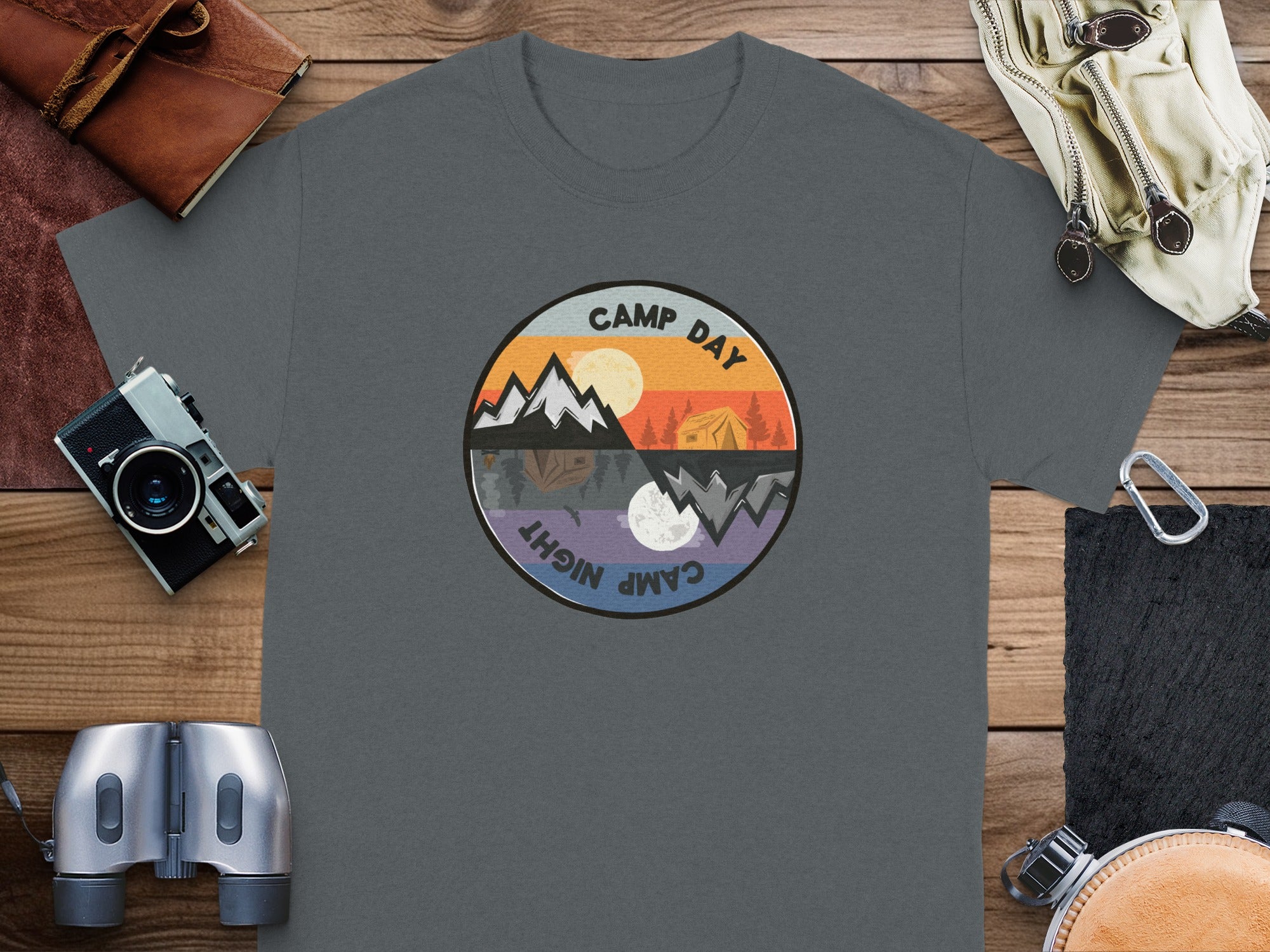 T-shirt with circular graphic depicting camping day and night scenes with text.