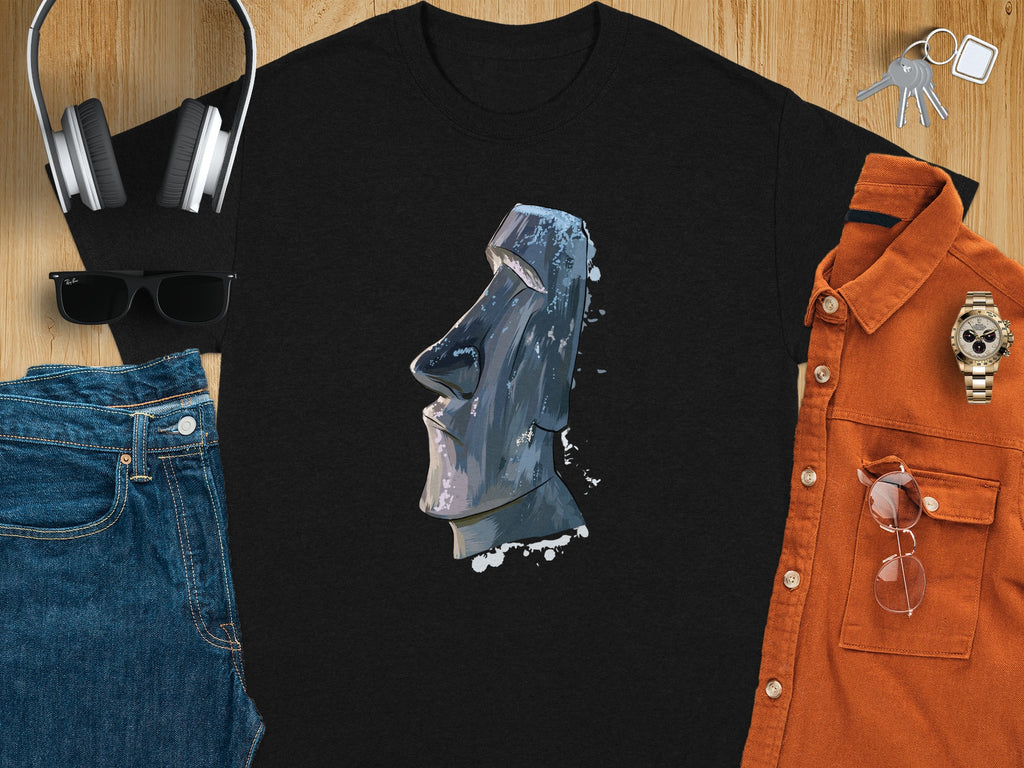 Black t-shirt with Moai statue graphic, styled with jeans, shirt, headphones, sunglasses, and keys.