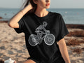 Black t-shirt with a white line drawing of a skeleton riding a bicycle.