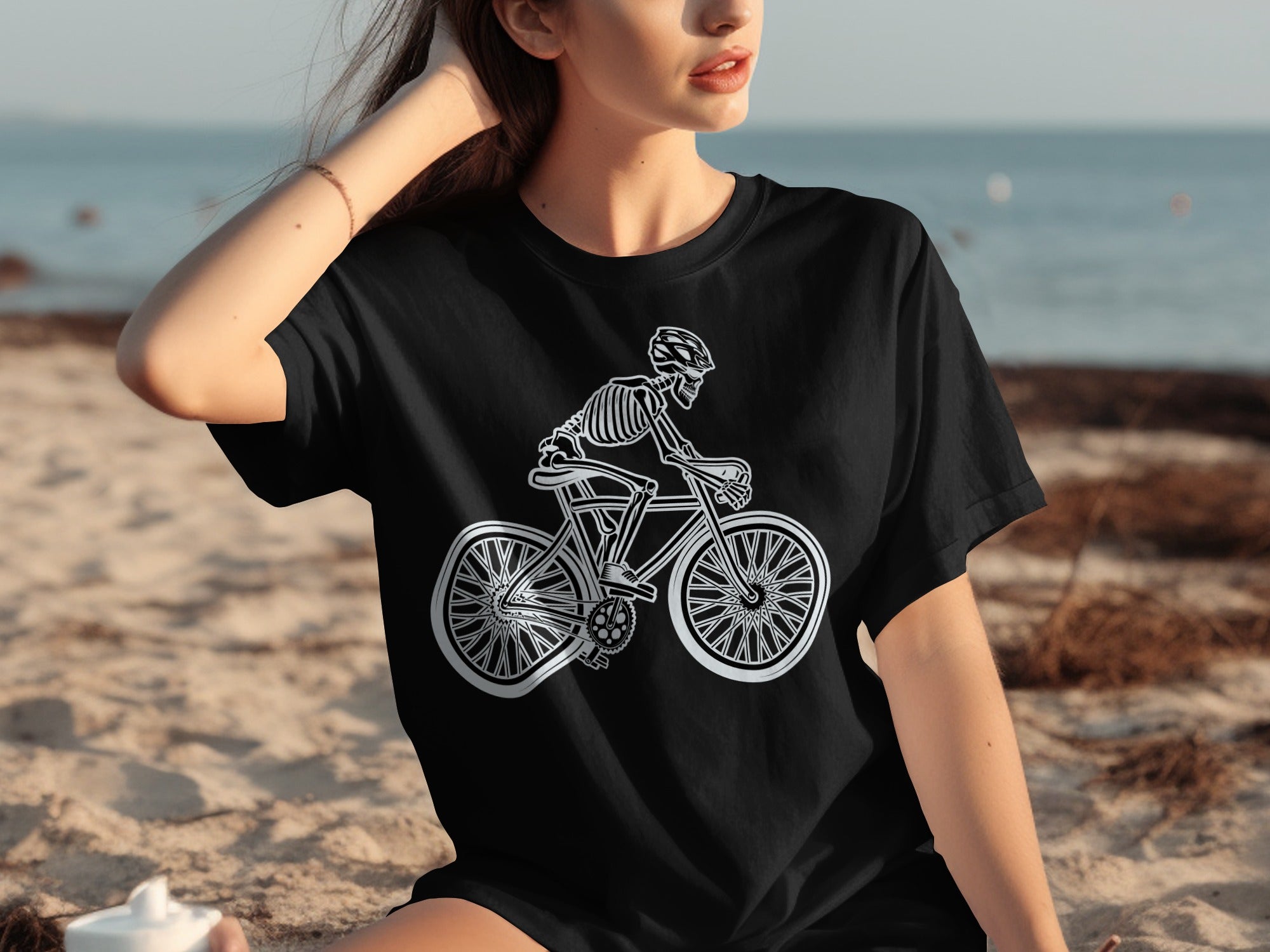 Black t-shirt with a white line drawing of a skeleton riding a bicycle.