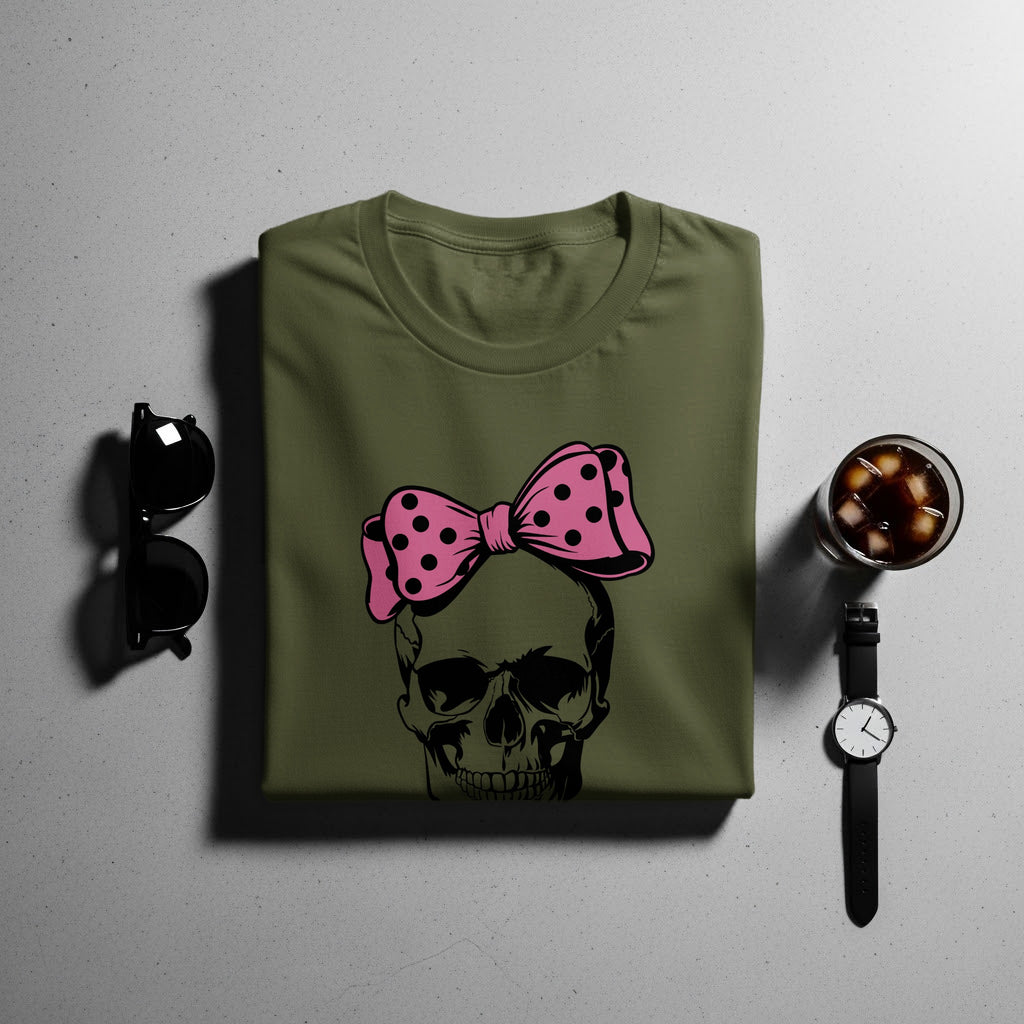 Olive t-shirt with black skull graphic and pink polka dot bow.