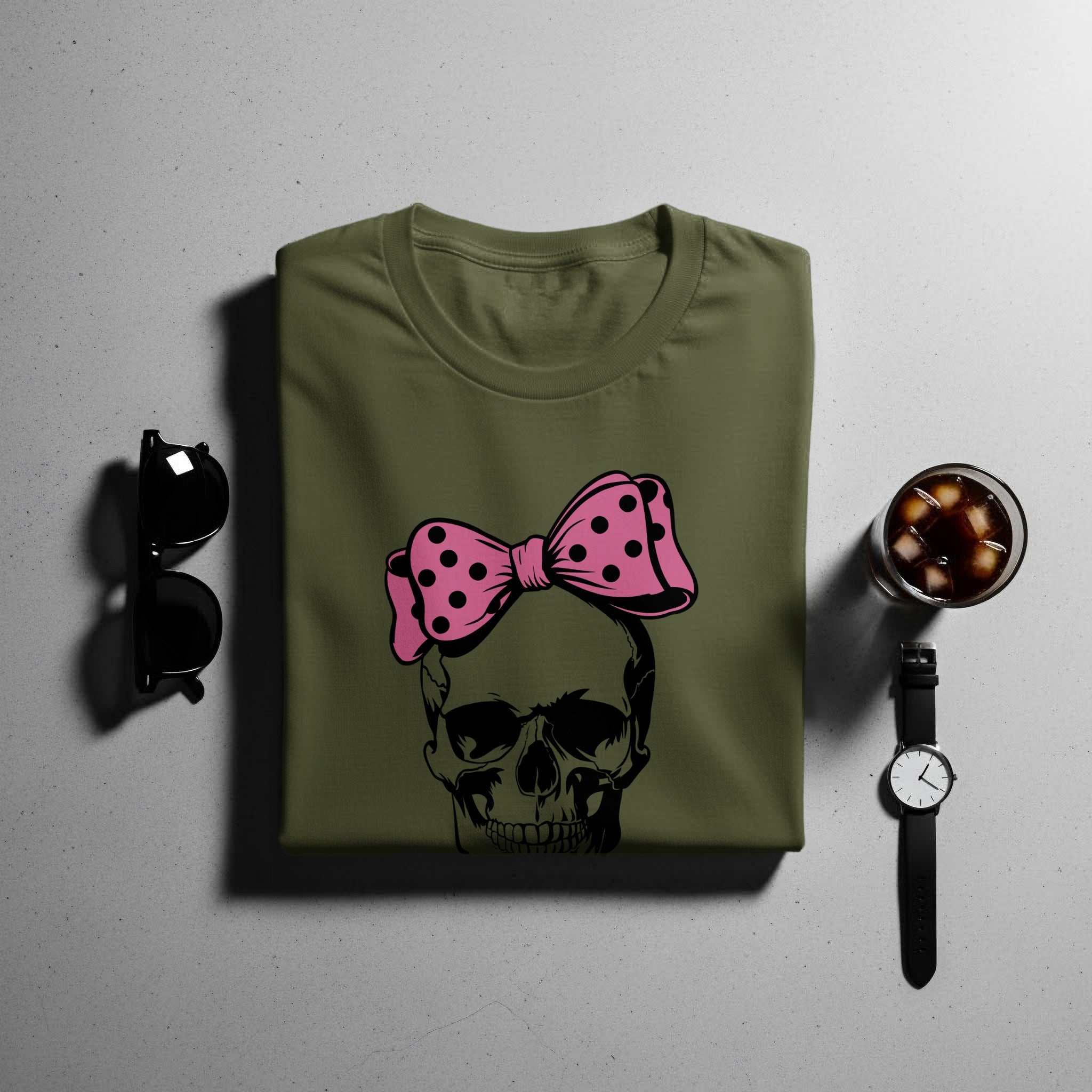 Olive t-shirt with black skull graphic and pink polka dot bow.