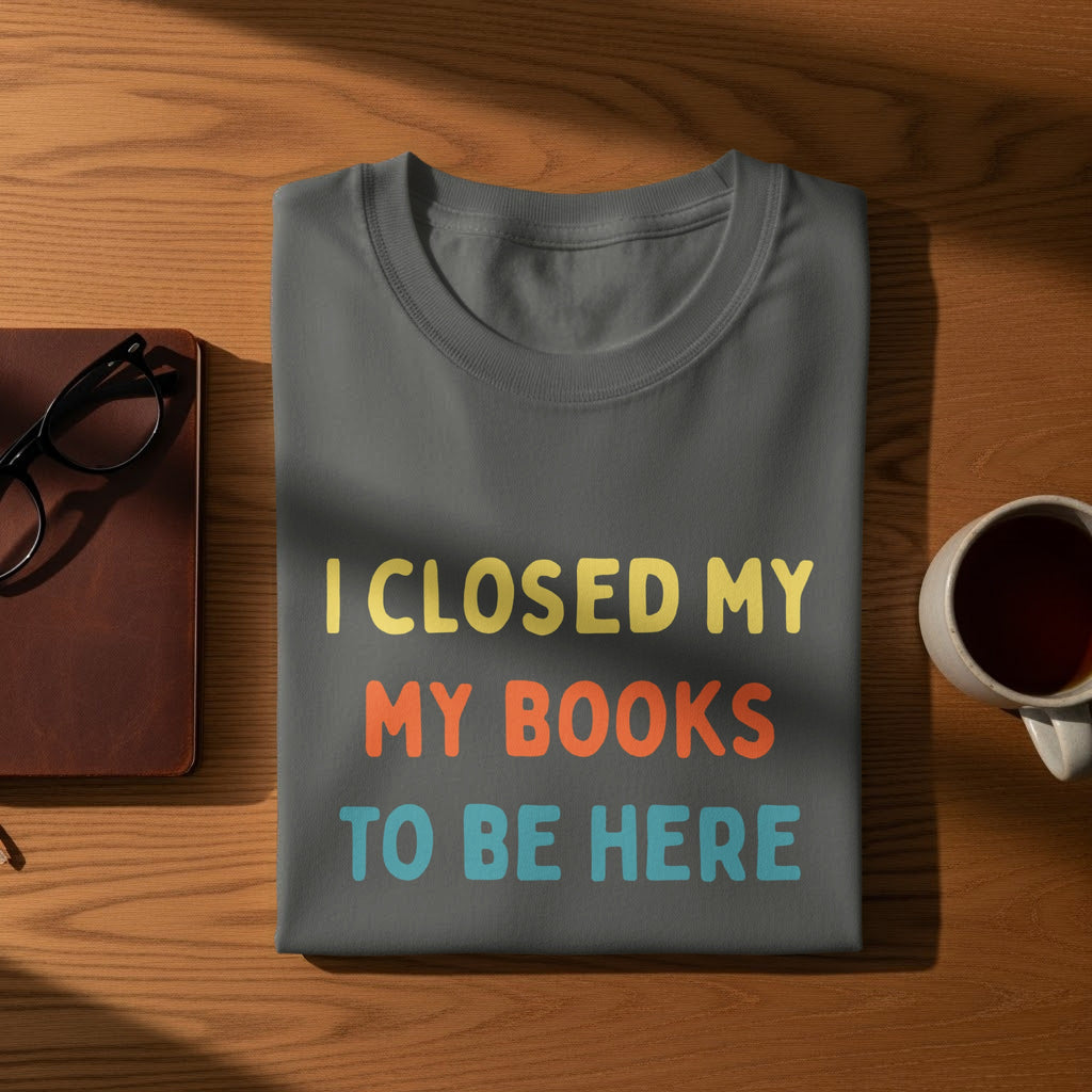 Grey t-shirt with text "I CLOSED MY MY BOOKS TO BE HERE" in yellow, orange, and blue.