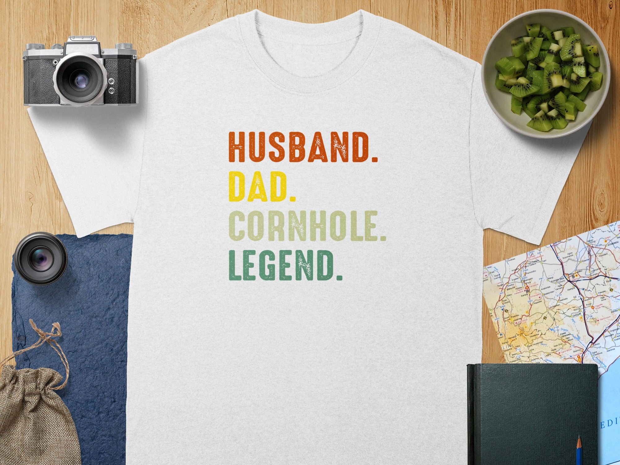 White t-shirt with "Husband. Dad. Cornhole. Legend." text in colored block letters.
