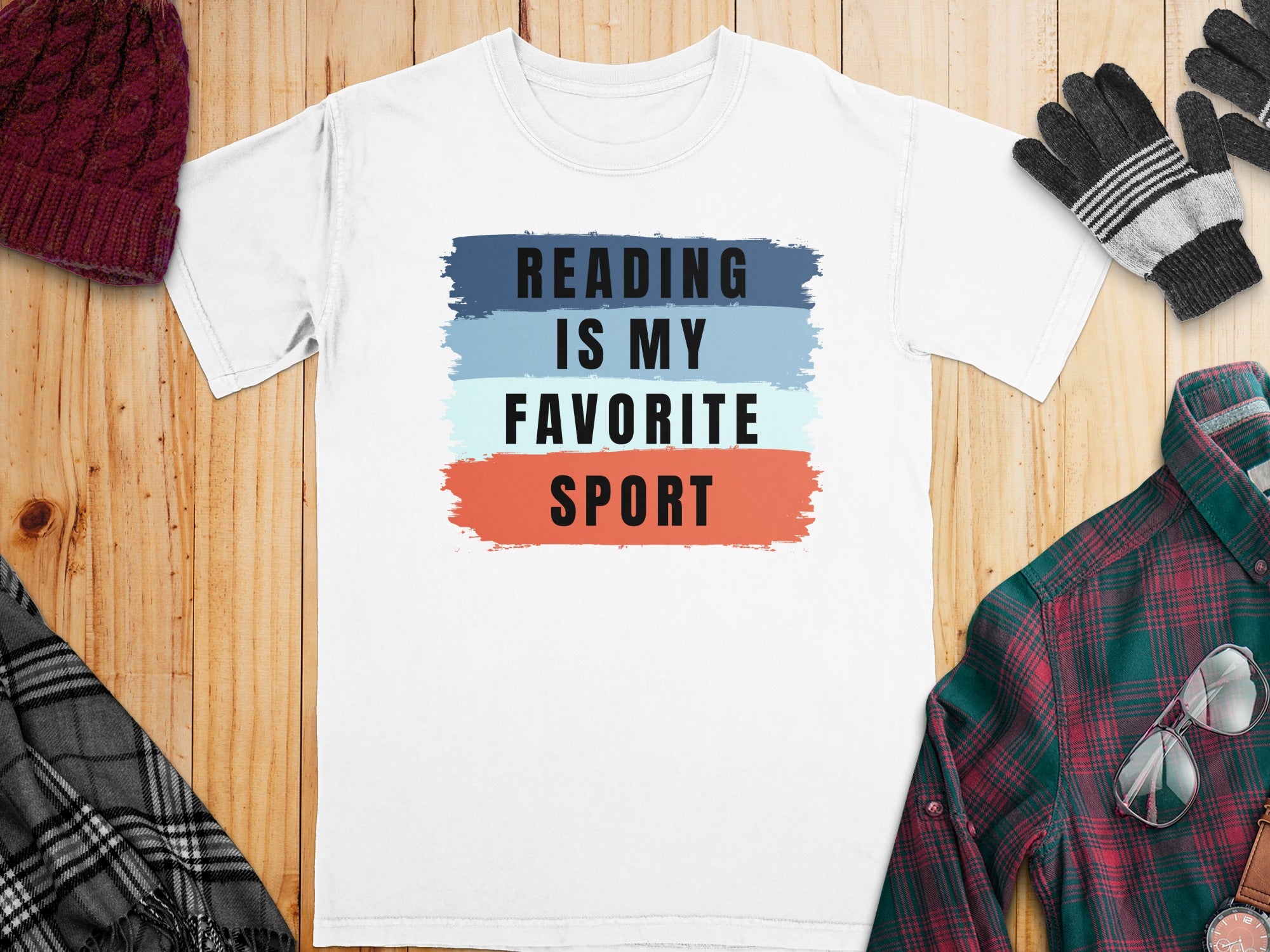 White t-shirt with "READING IS MY FAVORITE SPORT" printed above brush strokes.