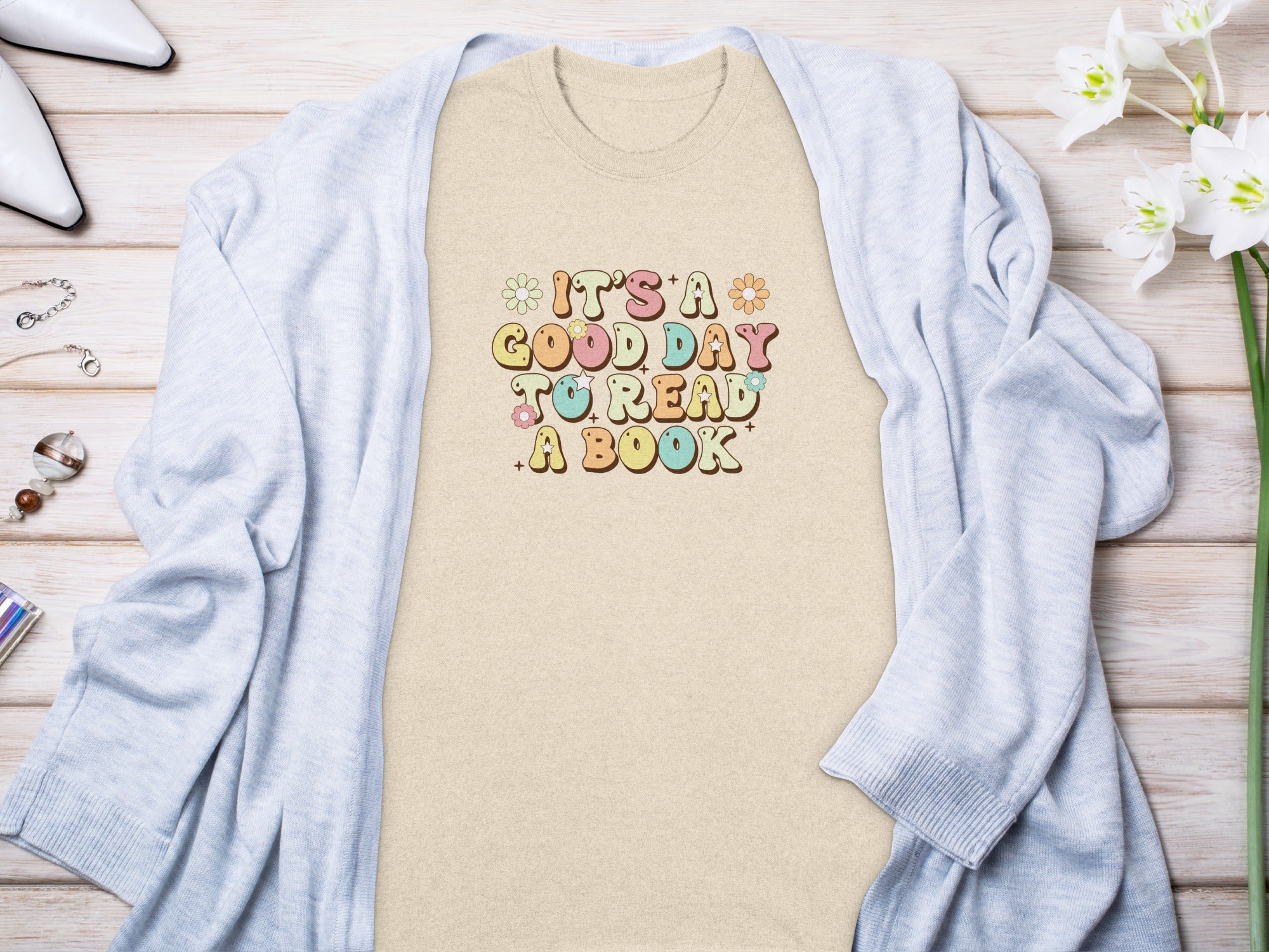 Tan t-shirt with text "IT'S A GOOD DAY TO READ A BOOK" and floral accents.
