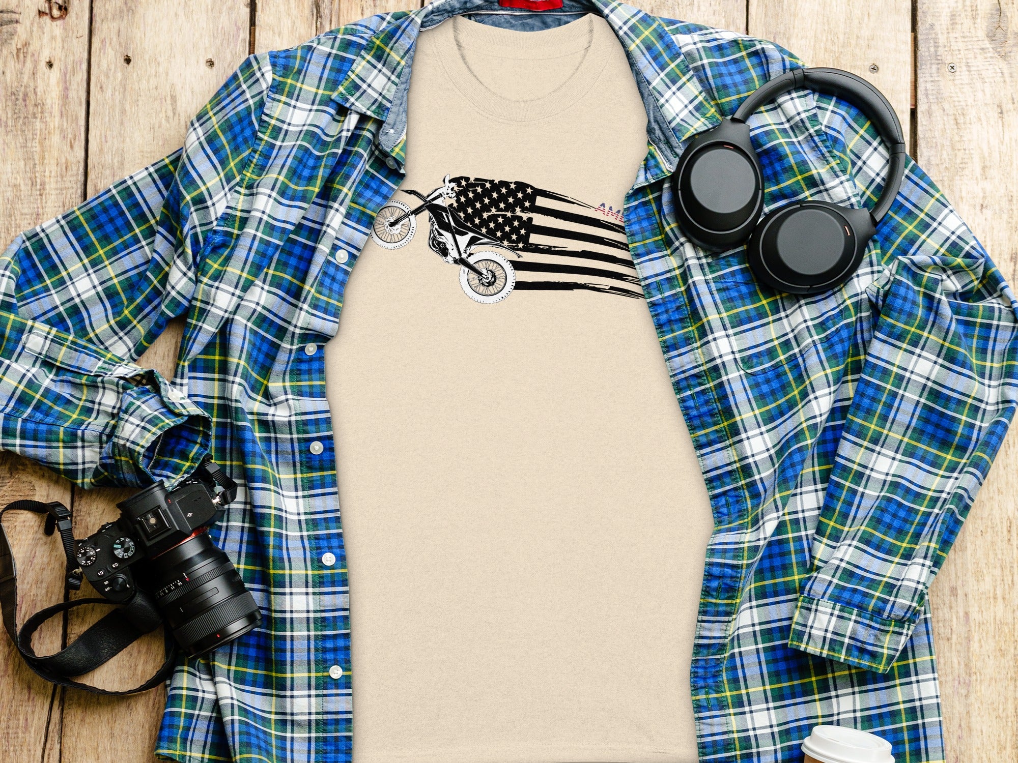 Tan t-shirt with a dirt bike and American flag graphic, laid flat.