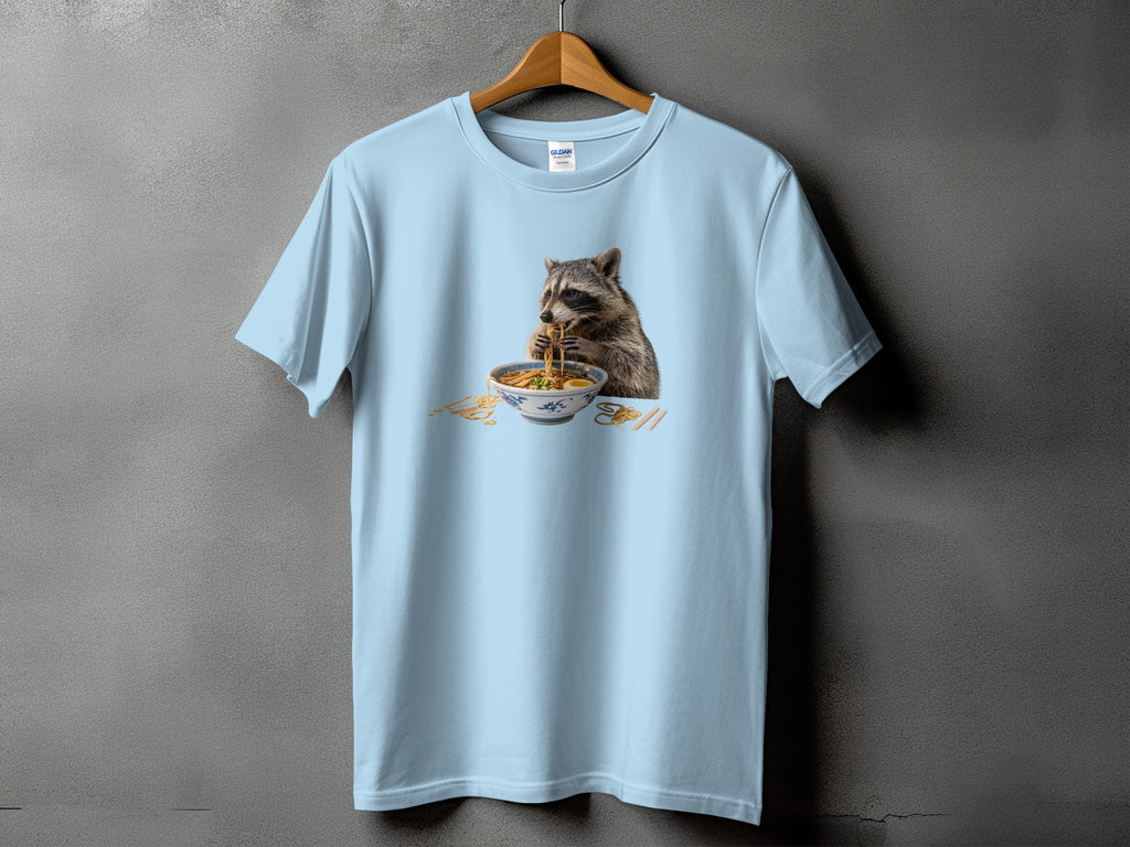 Light blue t-shirt with a graphic of a raccoon eating ramen.