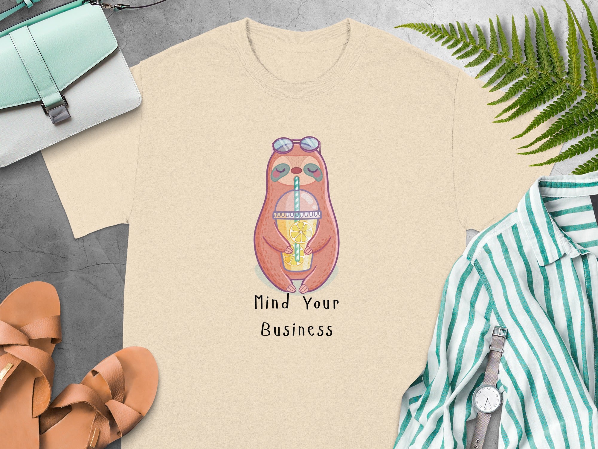 Cream t-shirt with a sloth graphic and the text "Mind Your Business".