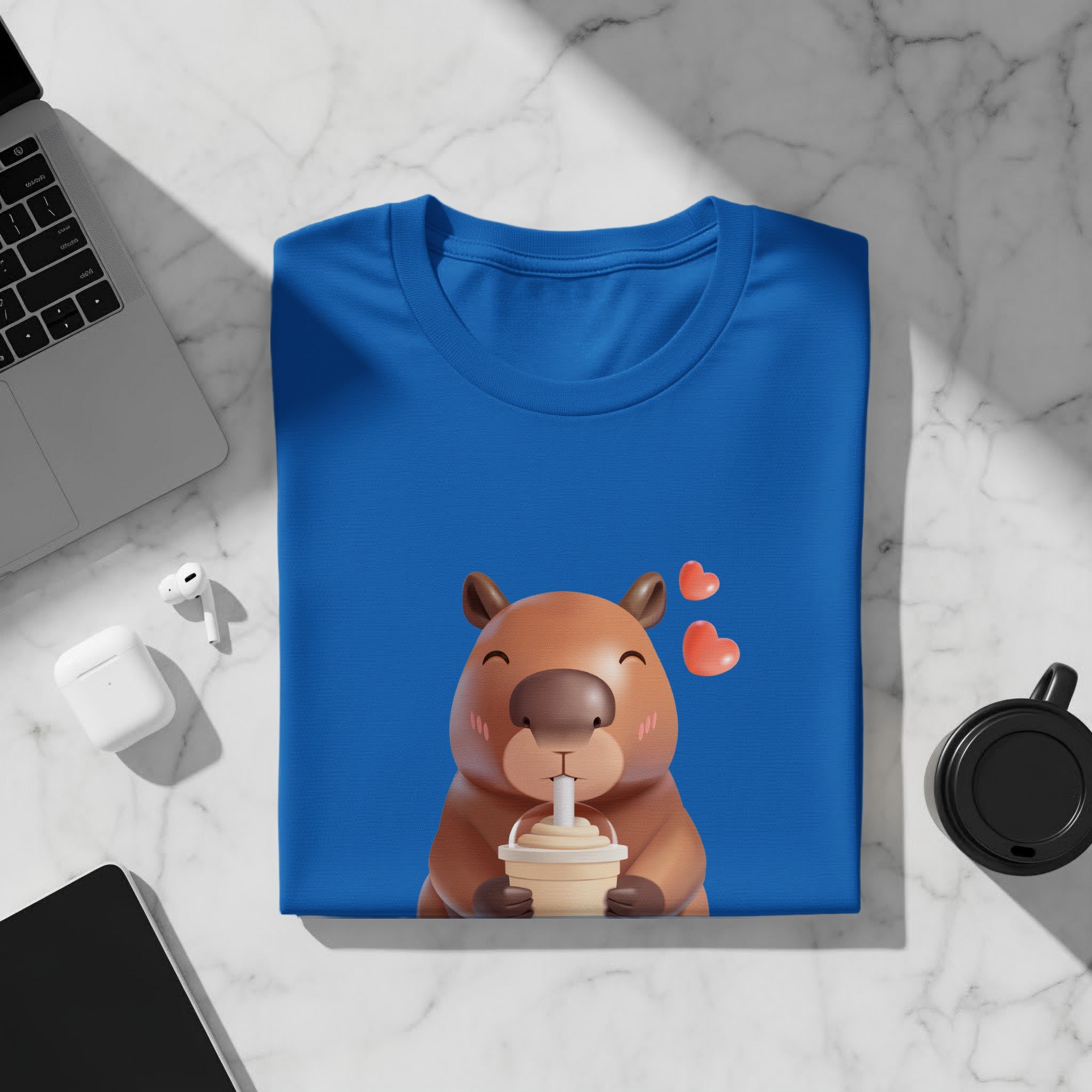 Blue t-shirt with a cartoon capybara drinking from a cup and two hearts.