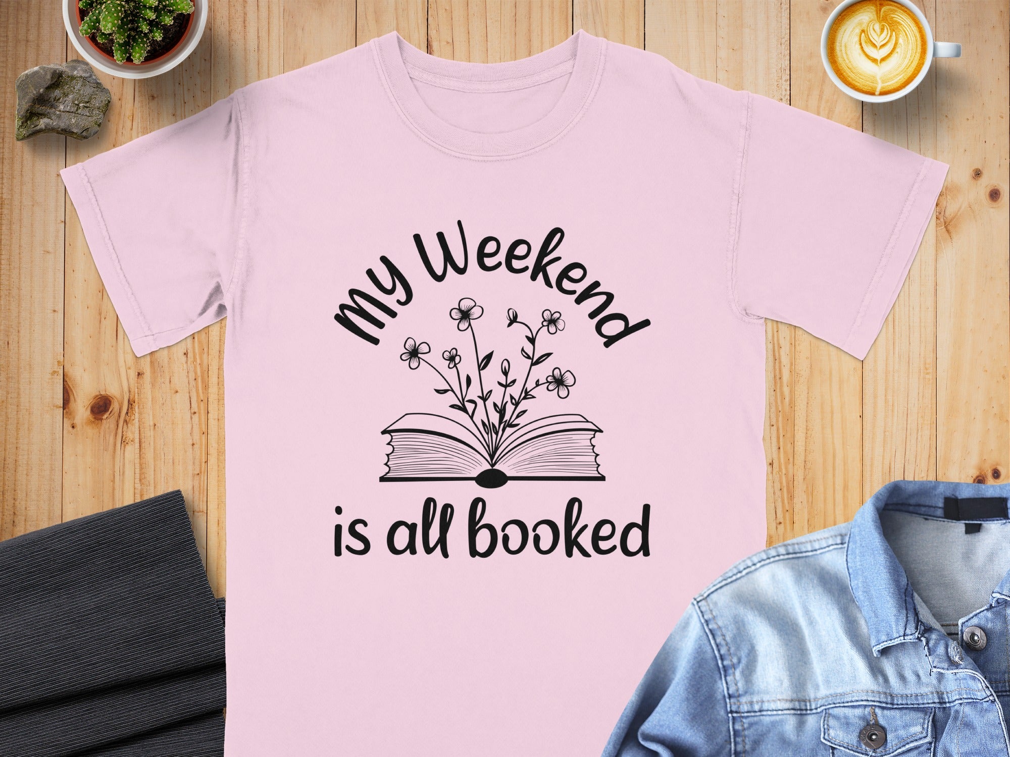 Pink t-shirt with "My Weekend is all booked" text and floral book graphic.