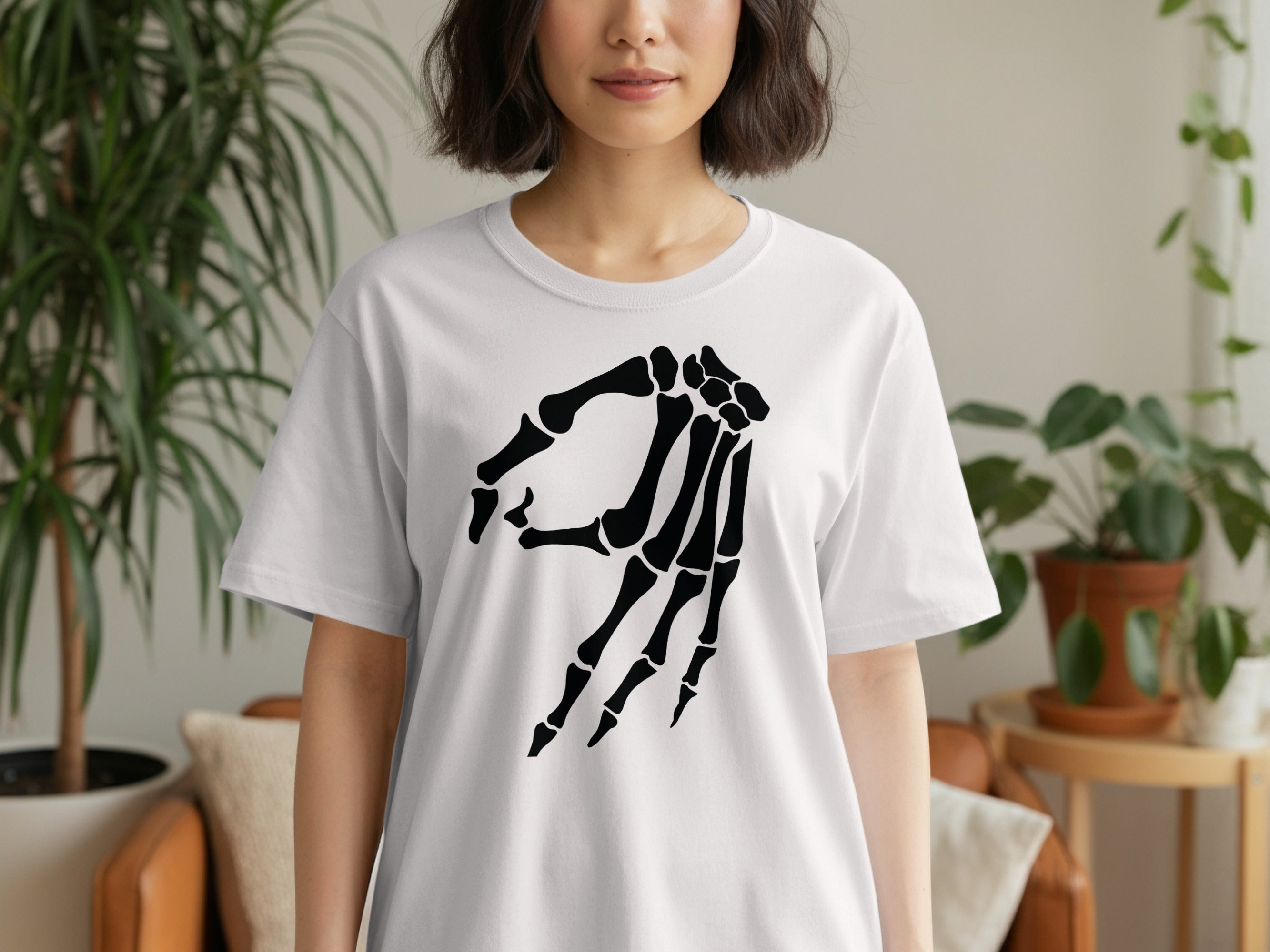 White t-shirt with black skeleton hand art on the chest.