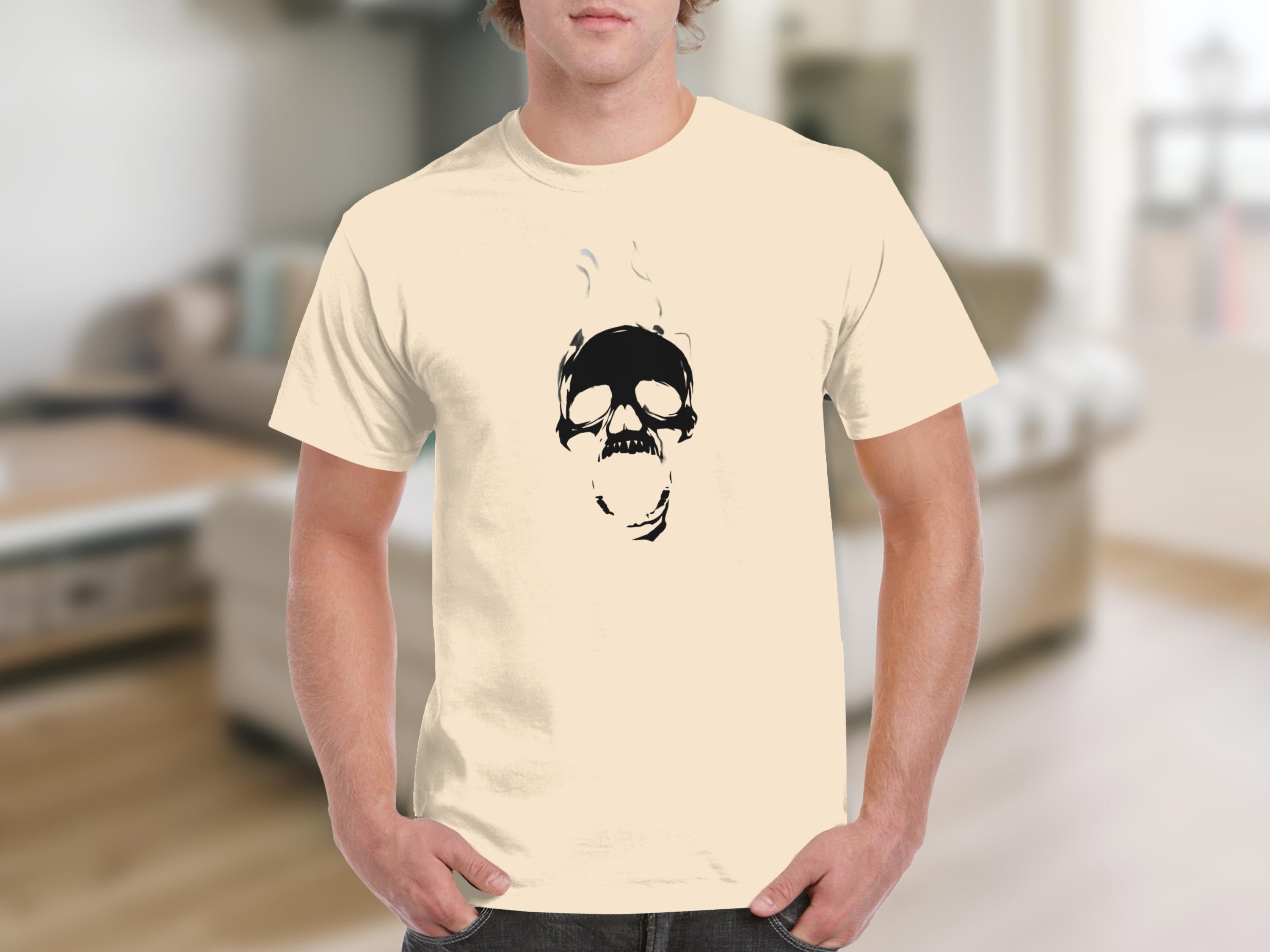 A man wears a cream t-shirt with a black graphic of a skull with smoke.