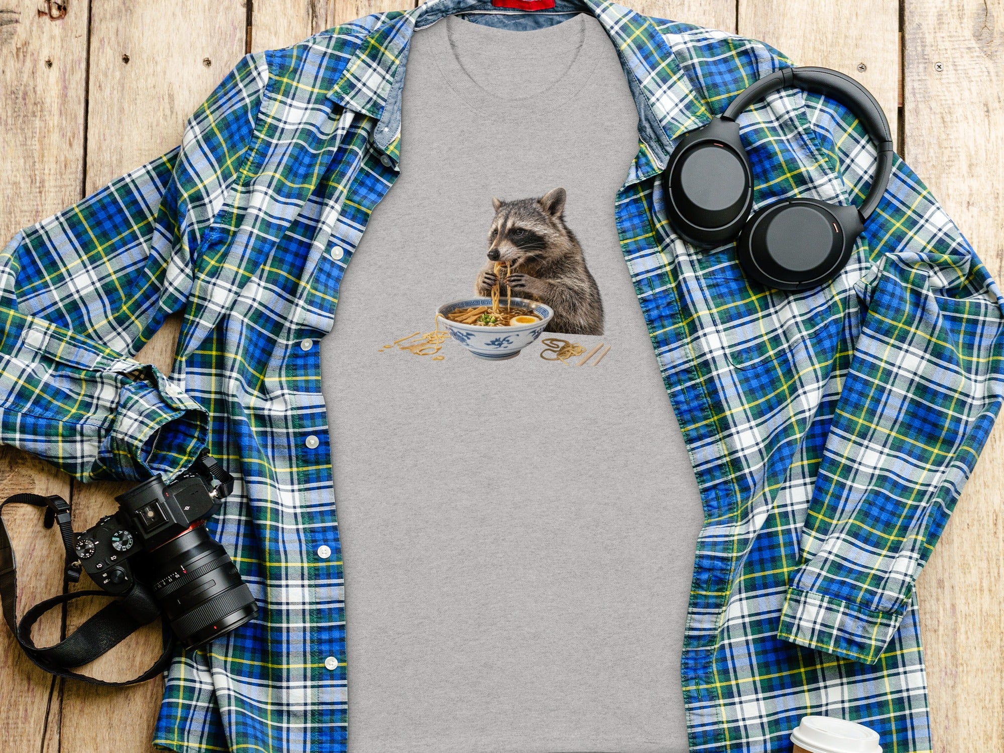 T-shirt with raccoon eating ramen graphic, layered with flannel shirt and accessories.