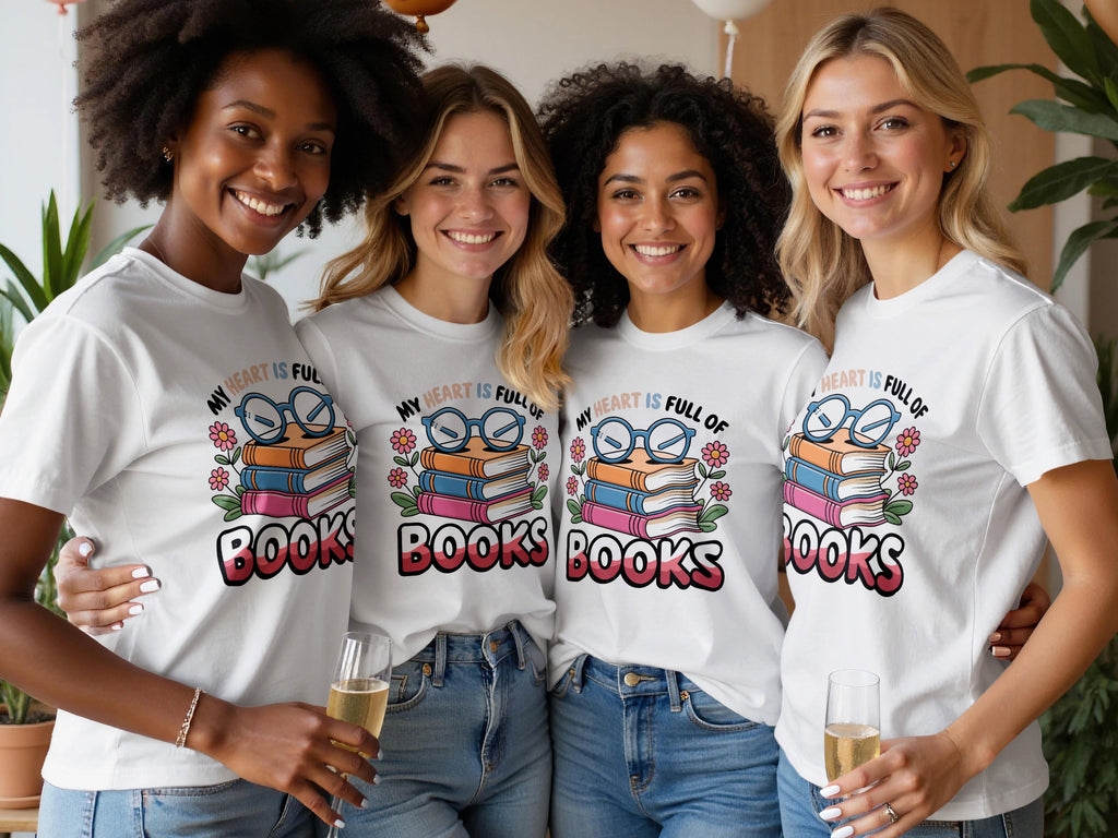 Four smiling women in white t-shirts featuring a graphic about books.