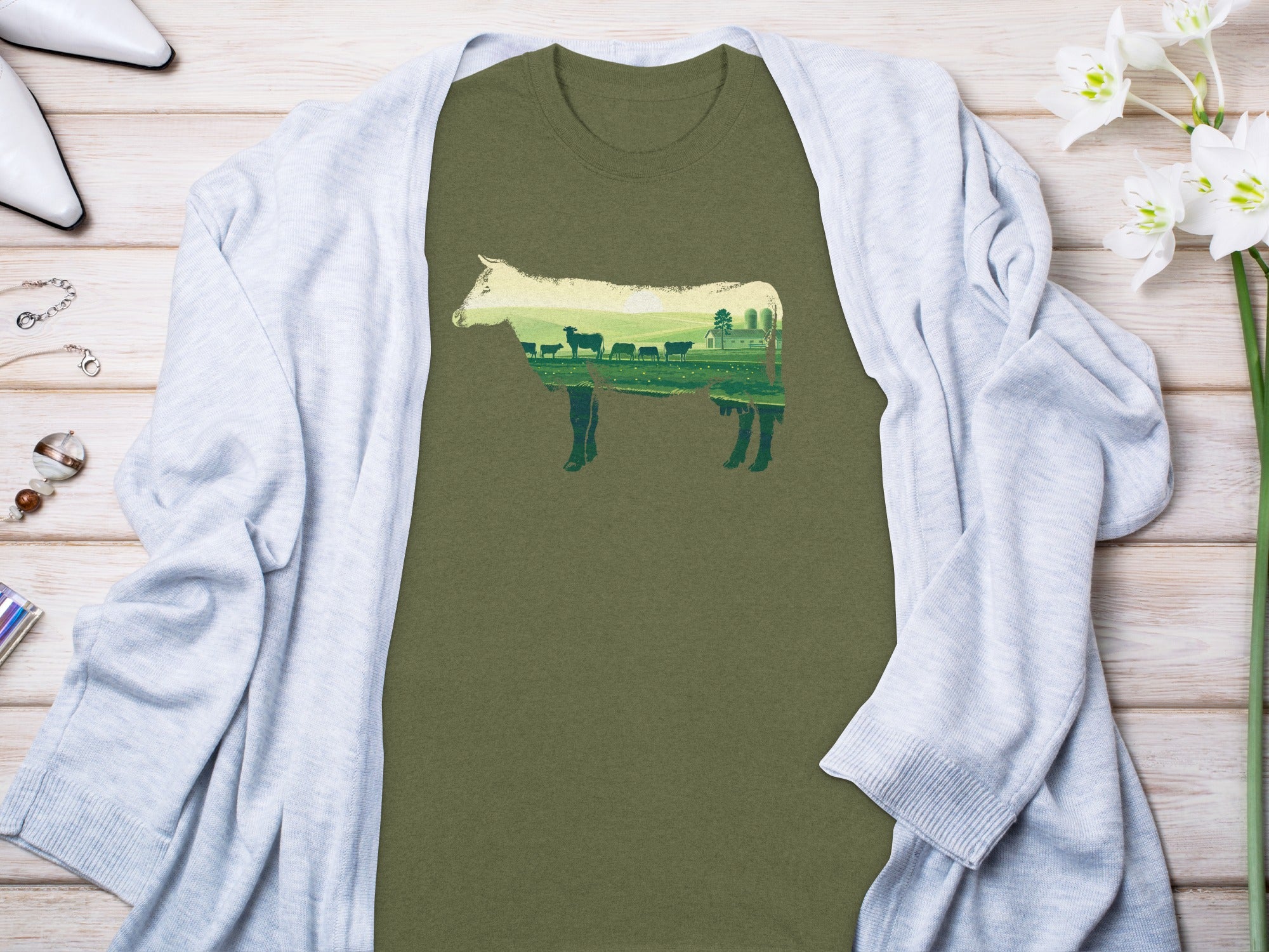 Green t-shirt with cow silhouette filled with farm landscape and cattle.