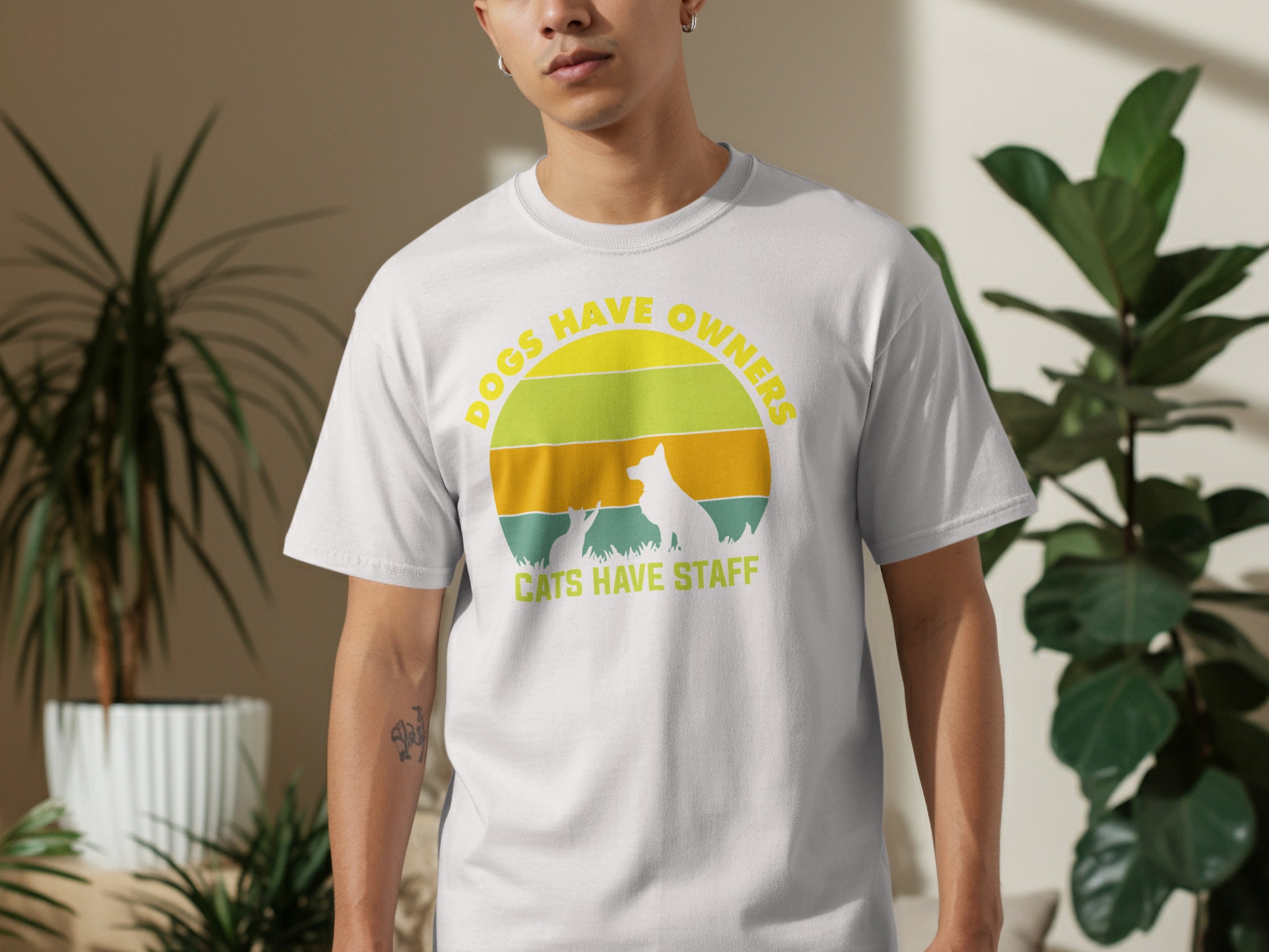 White t-shirt with graphic text "Dogs Have Owners, Cats Have Staff" and animal silhouettes.