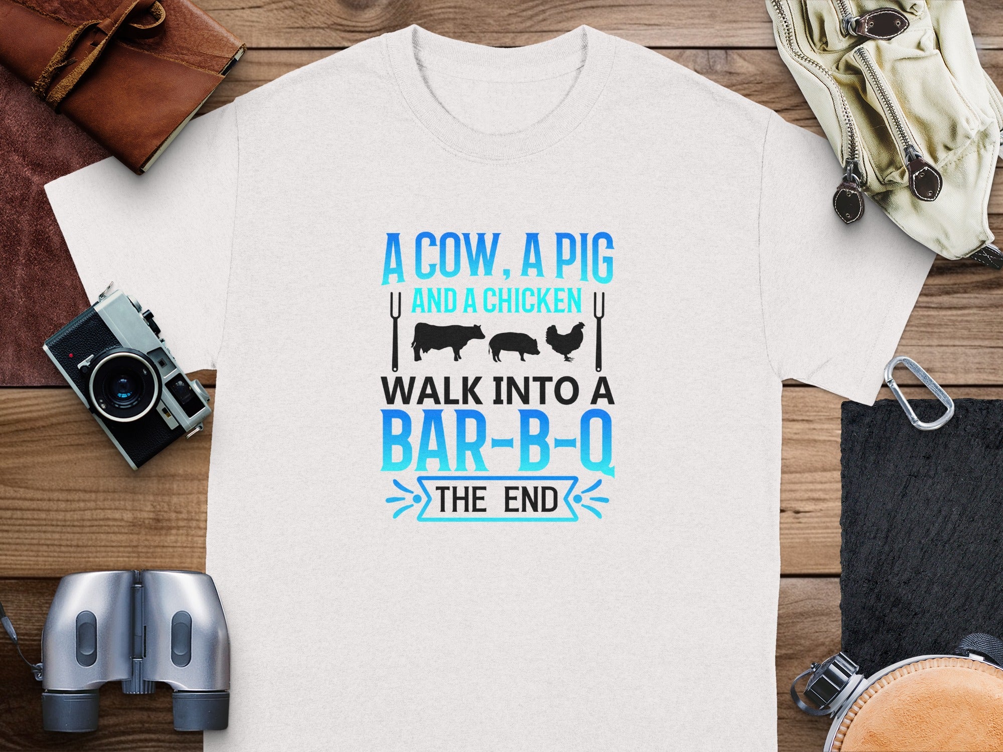 White t-shirt with "A cow, a pig and a chicken walk into a bar-b-q the end" graphic.