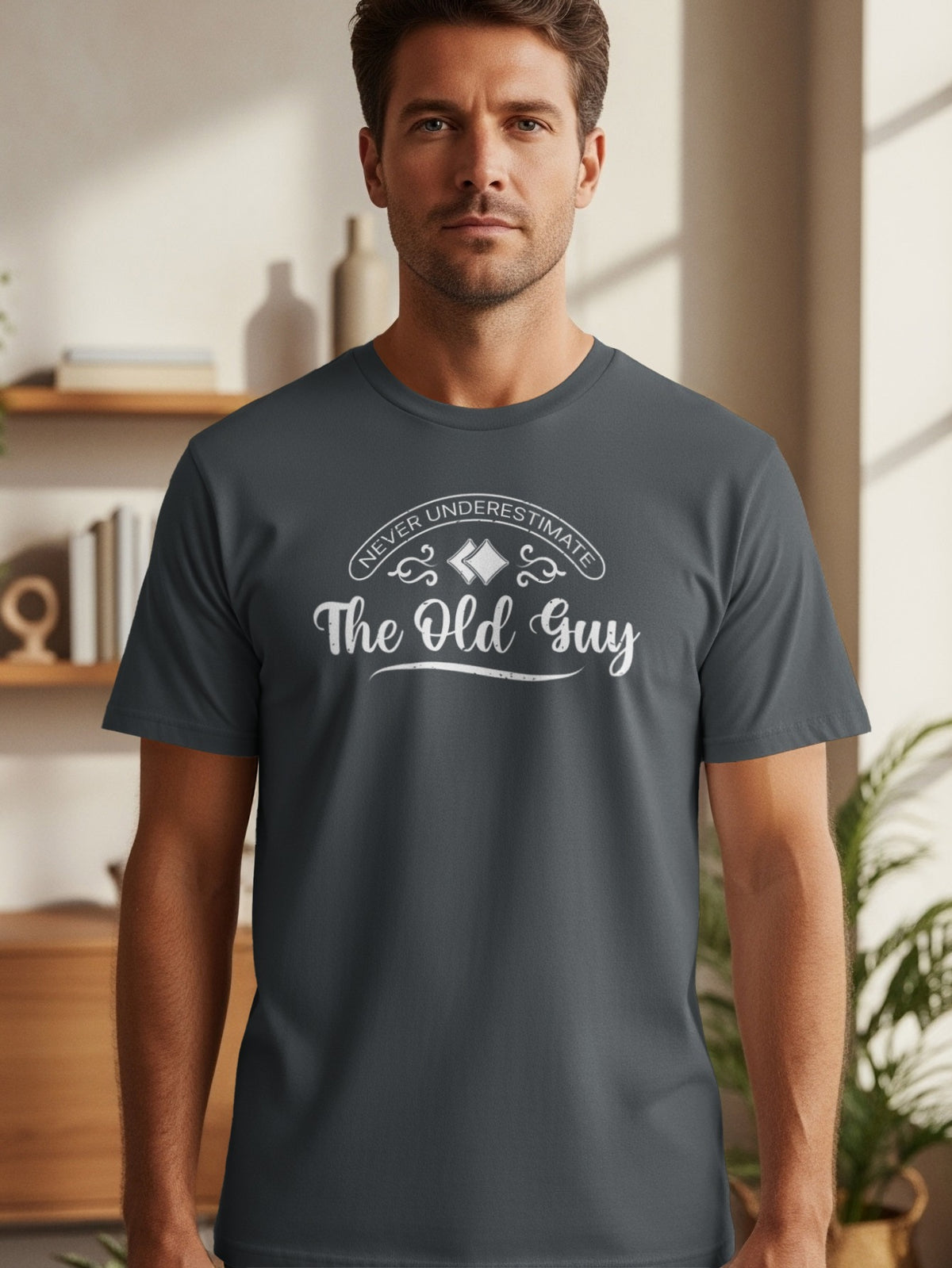 Dark gray t-shirt with white text that reads "NEVER UNDERESTIMATE The Old Guy".