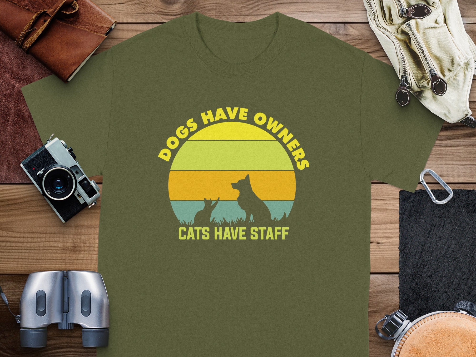 Olive t-shirt with circular graphic: "Dogs Have Owners, Cats Have Staff".