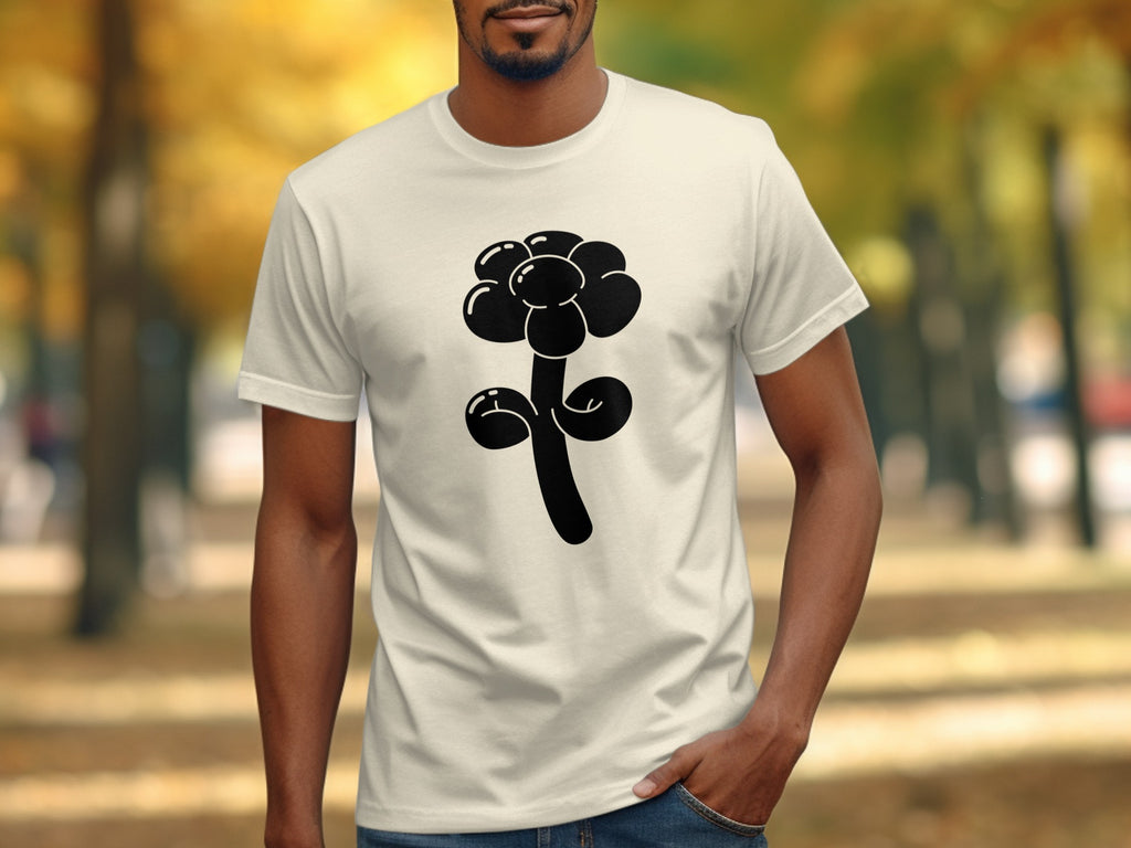 Cream t-shirt with black balloon flower graphic on a blurred park background.