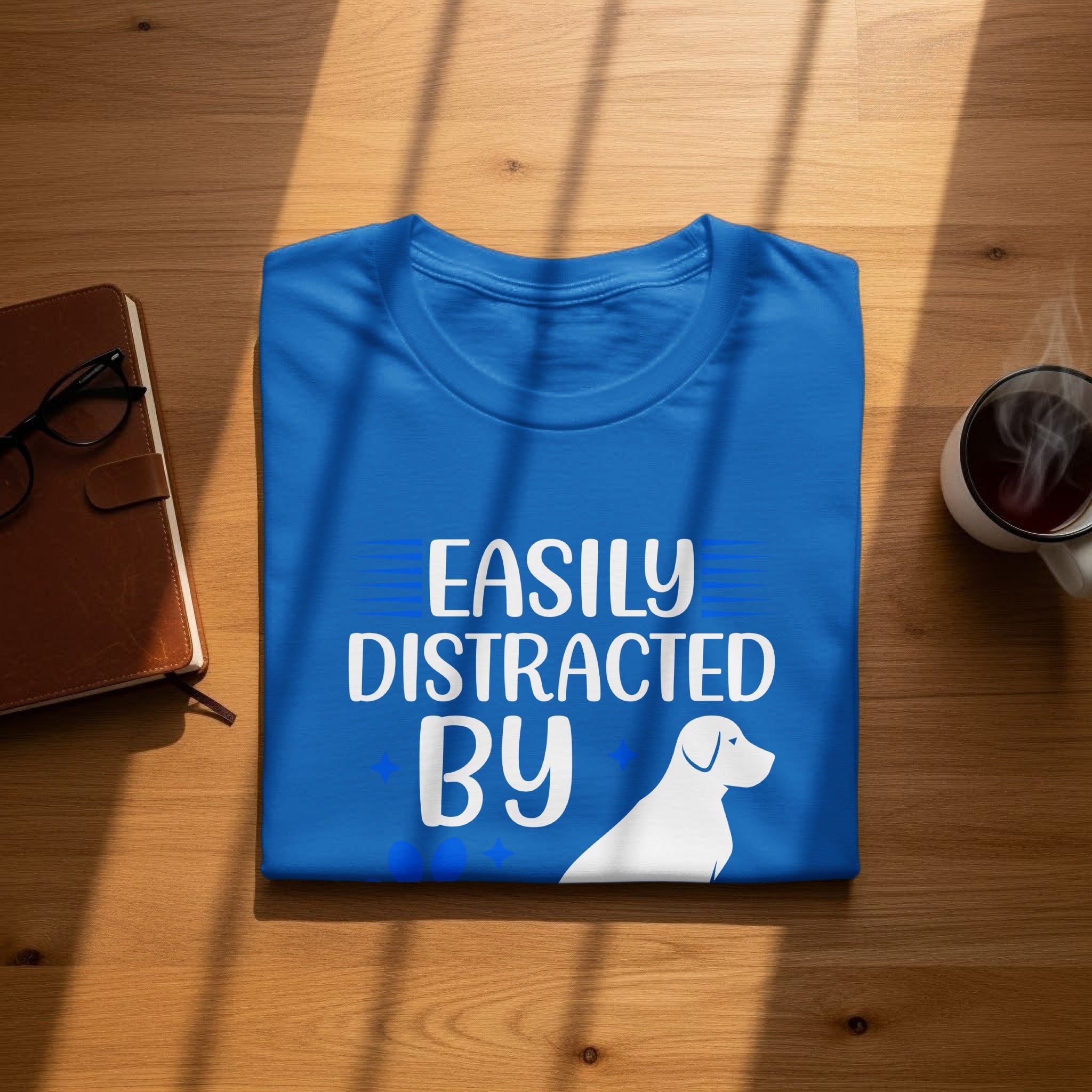 Blue t-shirt with white text "Easily Distracted By Dogs" and white dog silhouette.