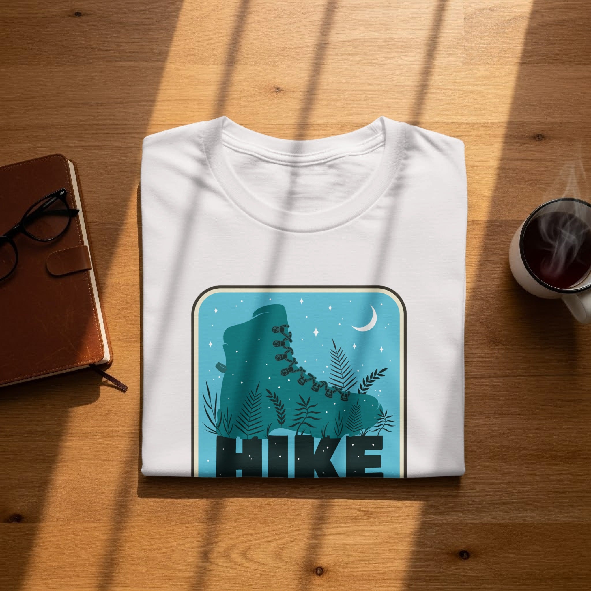 White t-shirt with "Hike" graphic featuring a teal hiking boot and woodland scene.