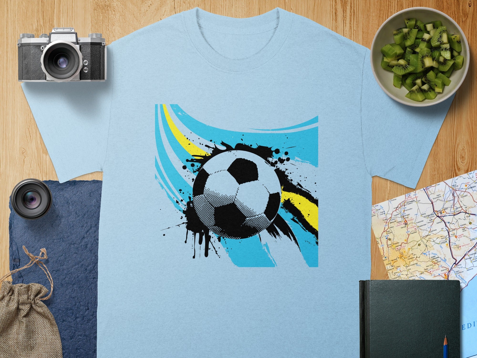 Light blue t-shirt with a graphic of a soccer ball and abstract paint splatters.