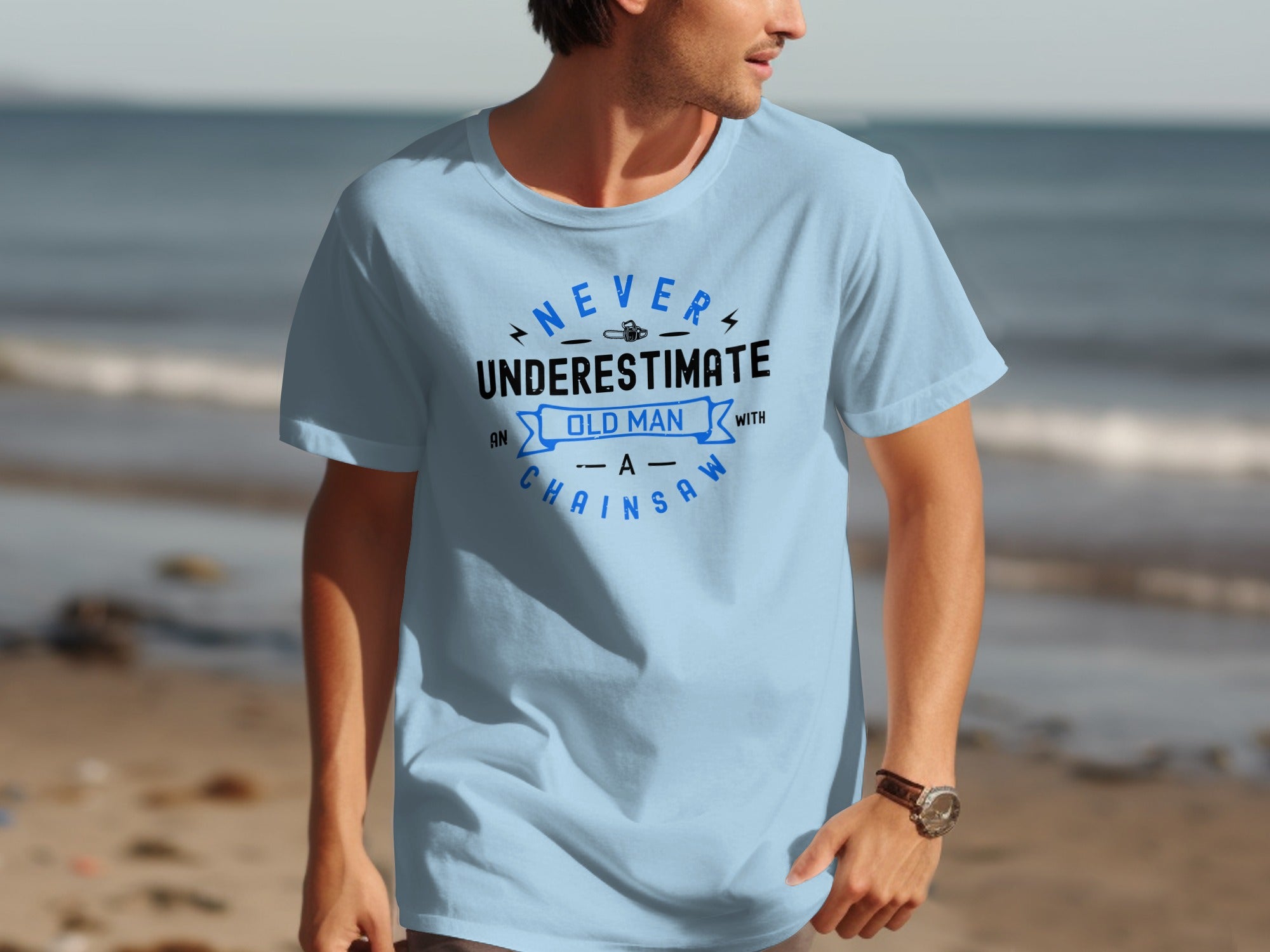 Light blue t-shirt with "Never Underestimate an Old Man with a Chainsaw" graphic.