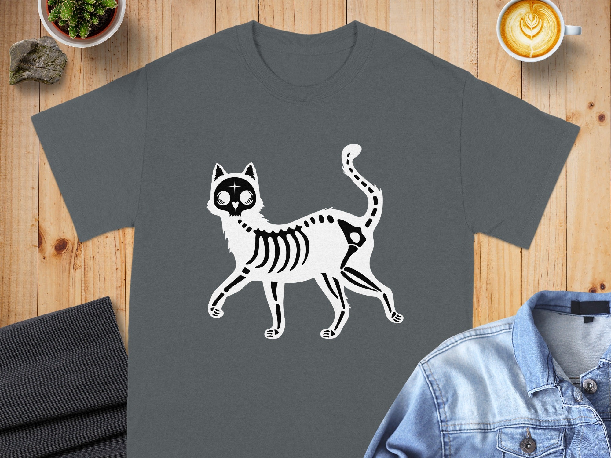 T-shirt with a black and white skeleton cat graphic on a wooden background.