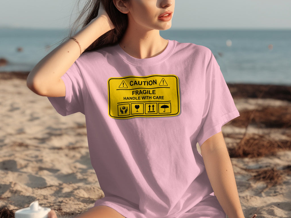 Pink t-shirt with "CAUTION FRAGILE HANDLE WITH CARE" text and icons.