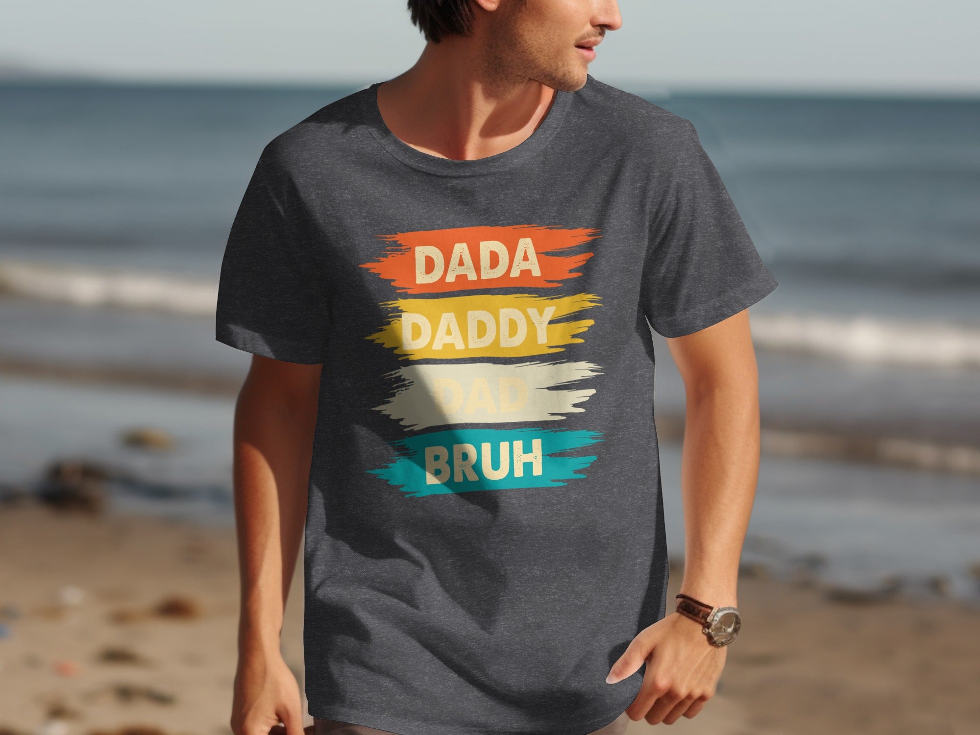 Dark gray t-shirt with text "Dada Daddy Dad Bruh" in colorful brushstrokes.