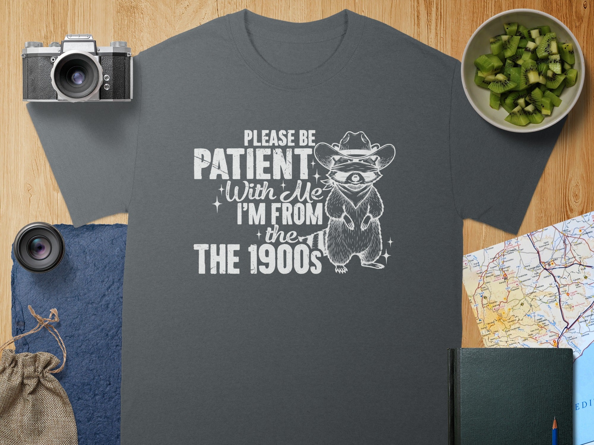 T-shirt with text "PLEASE BE PATIENT With Me I'M FROM the 1900s" and raccoon graphic.