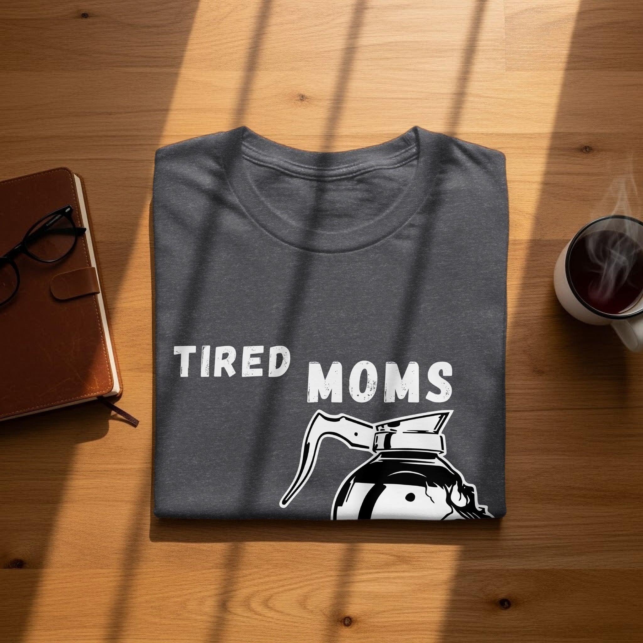 Dark gray t-shirt with white "TIRED MOMS" text and coffee pot graphic.