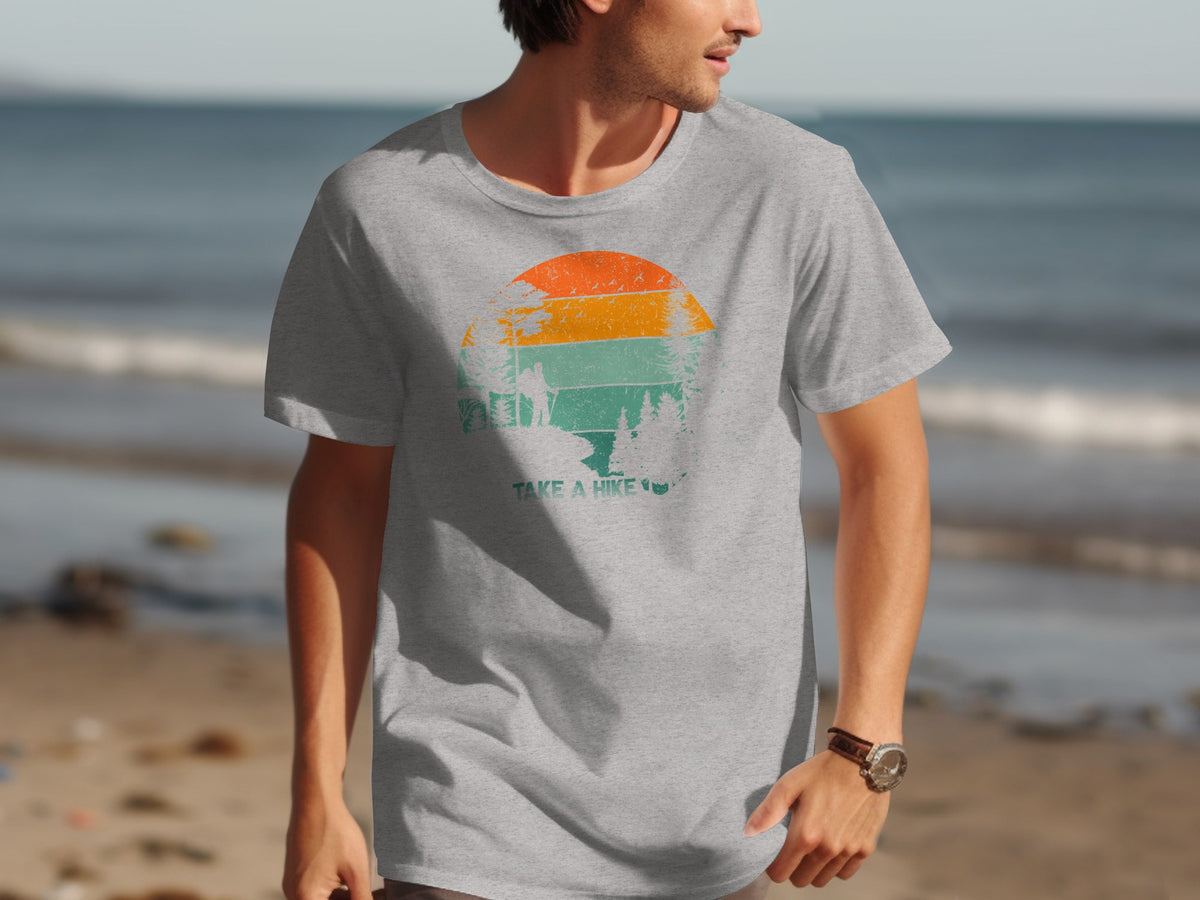 Grey t-shirt with a distressed graphic of a sunset over trees and mountains, text reads "TAKE A HIKE".