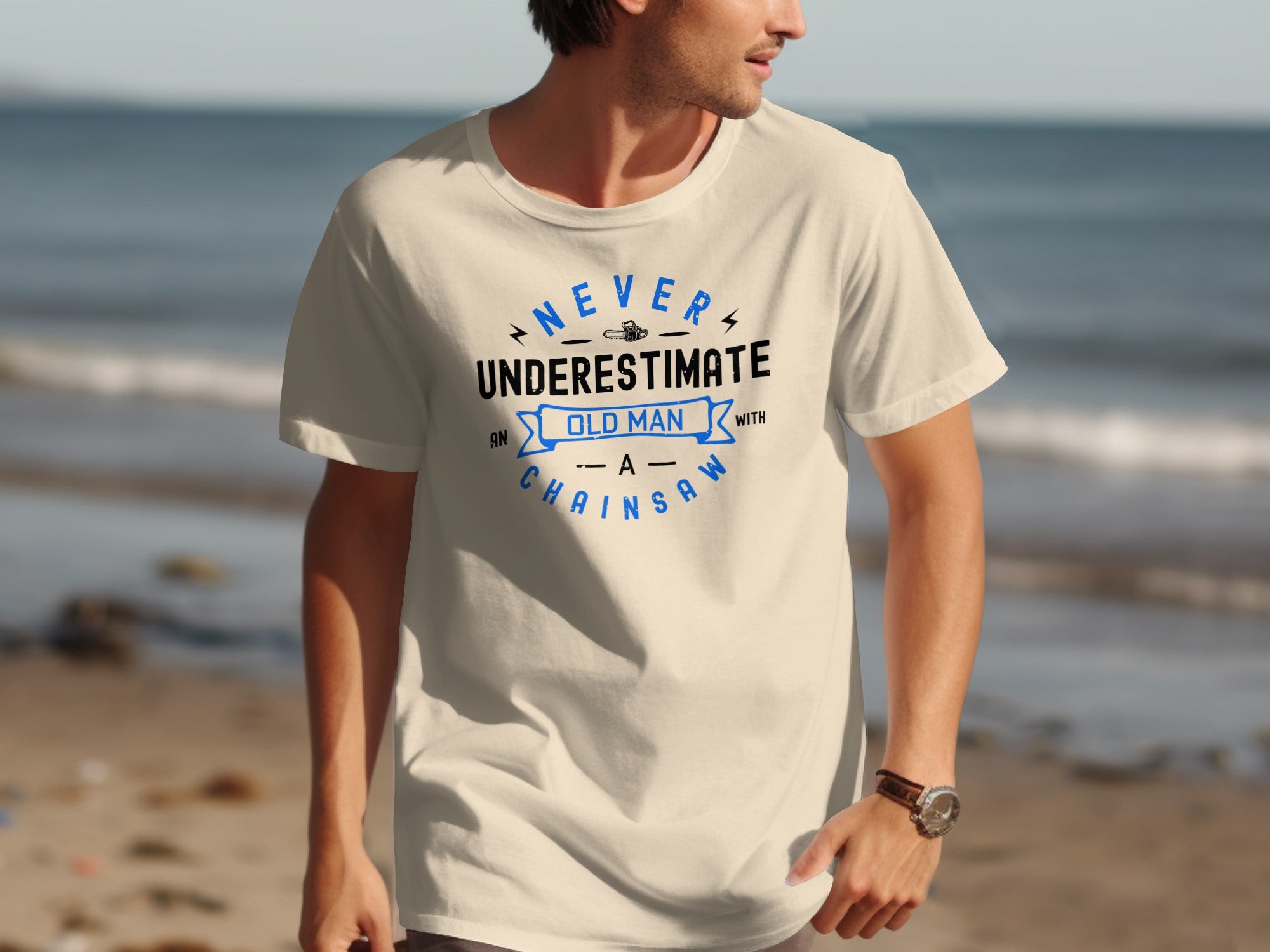 Cream t-shirt with blue text: Never underestimate an old man with a chainsaw.