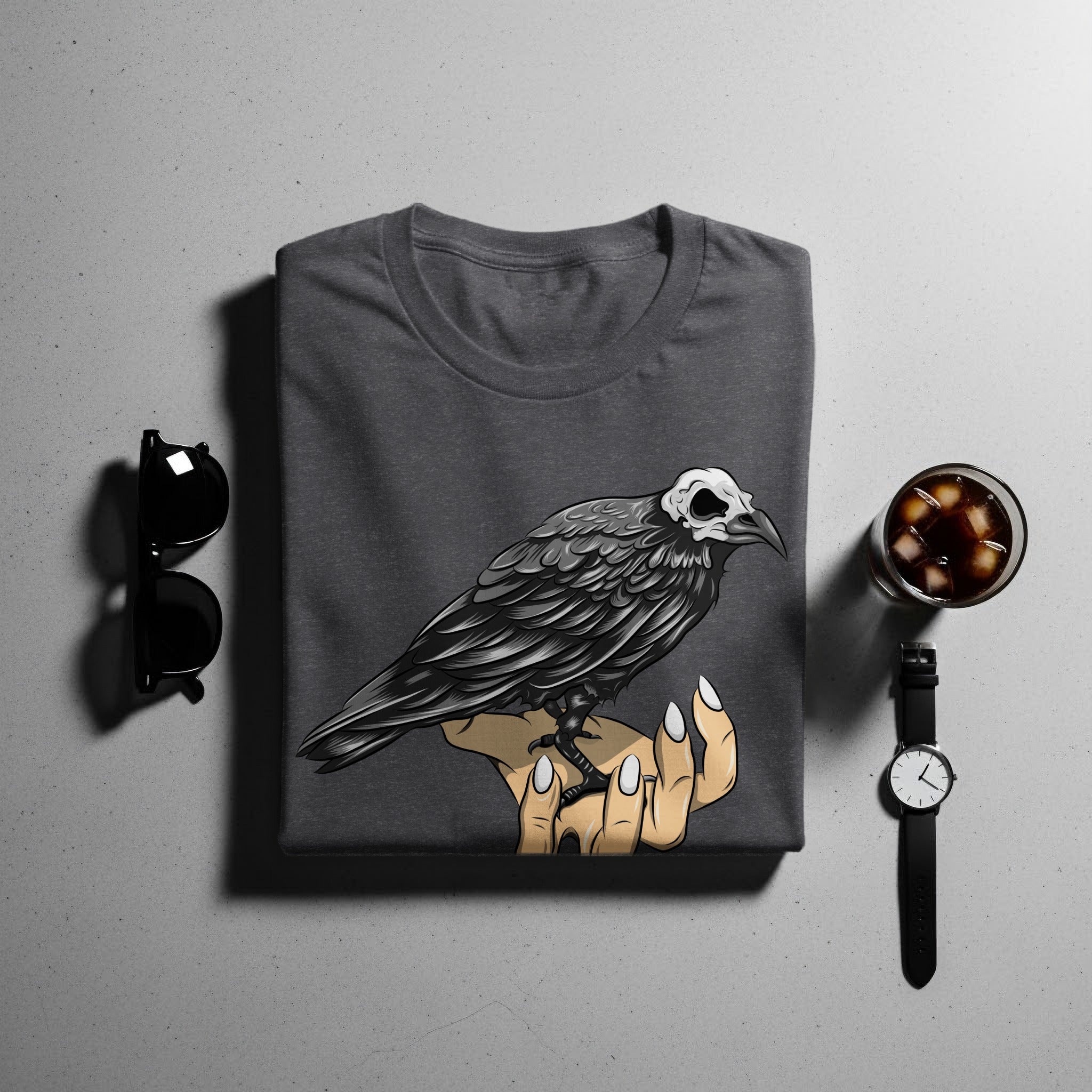 Dark grey t-shirt with a crow skull graphic illustration on a hand.