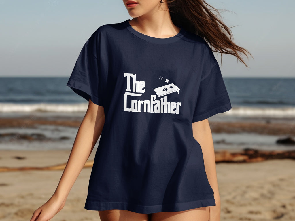 Navy t-shirt with white text "The Cornfather" and a cornhole board graphic.