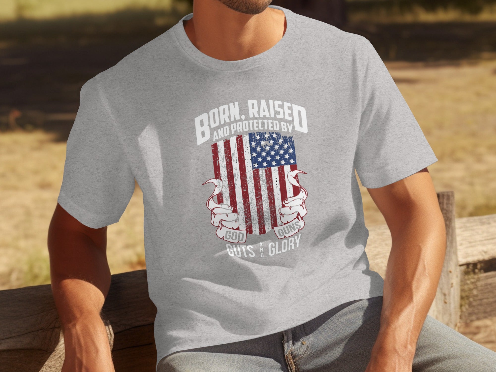 Grey t-shirt with patriotic graphic: "Born, Raised and Protected By God, Guns, Guts & Glory."