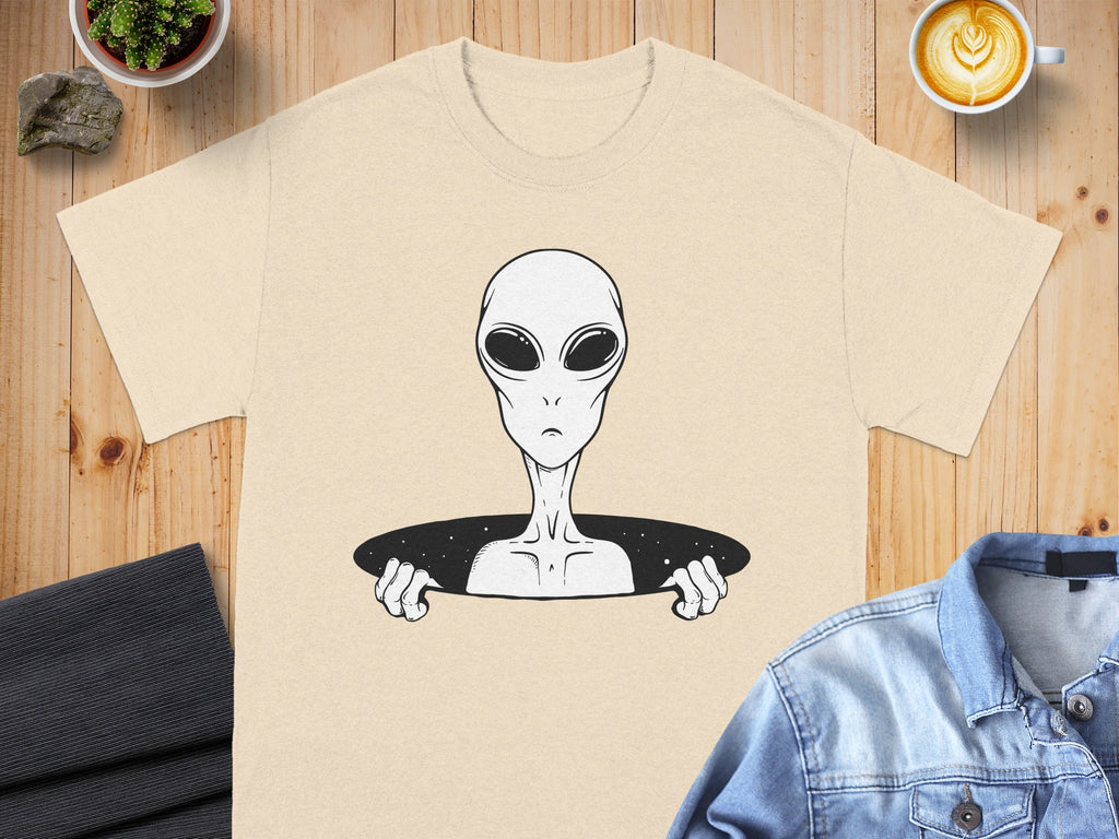 Cream t-shirt with black and white alien graphic reaching out from a starry hole.