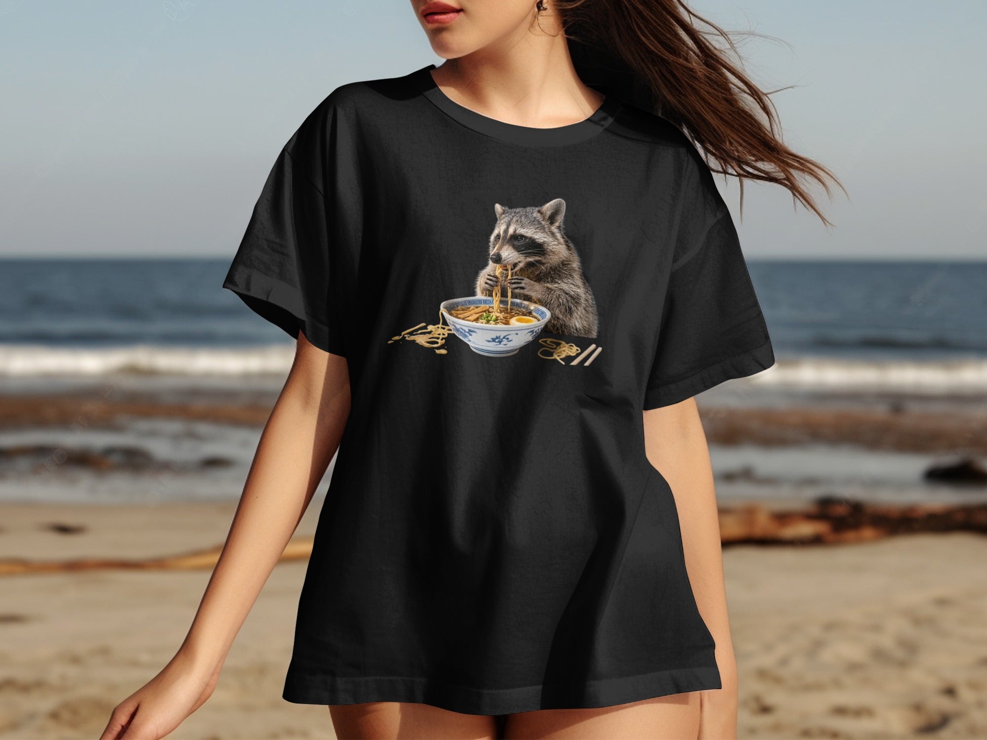 Black t-shirt with a raccoon eating ramen graphic on the front.