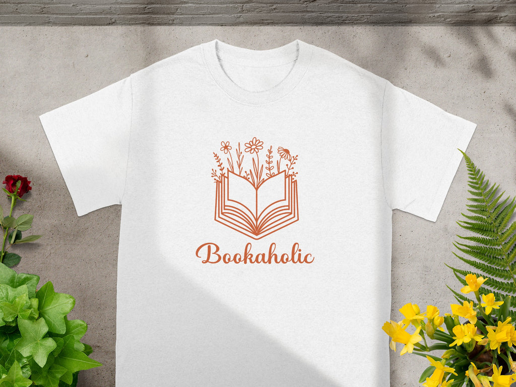 White t-shirt with an orange book and flower graphic and "Bookaholic" text.