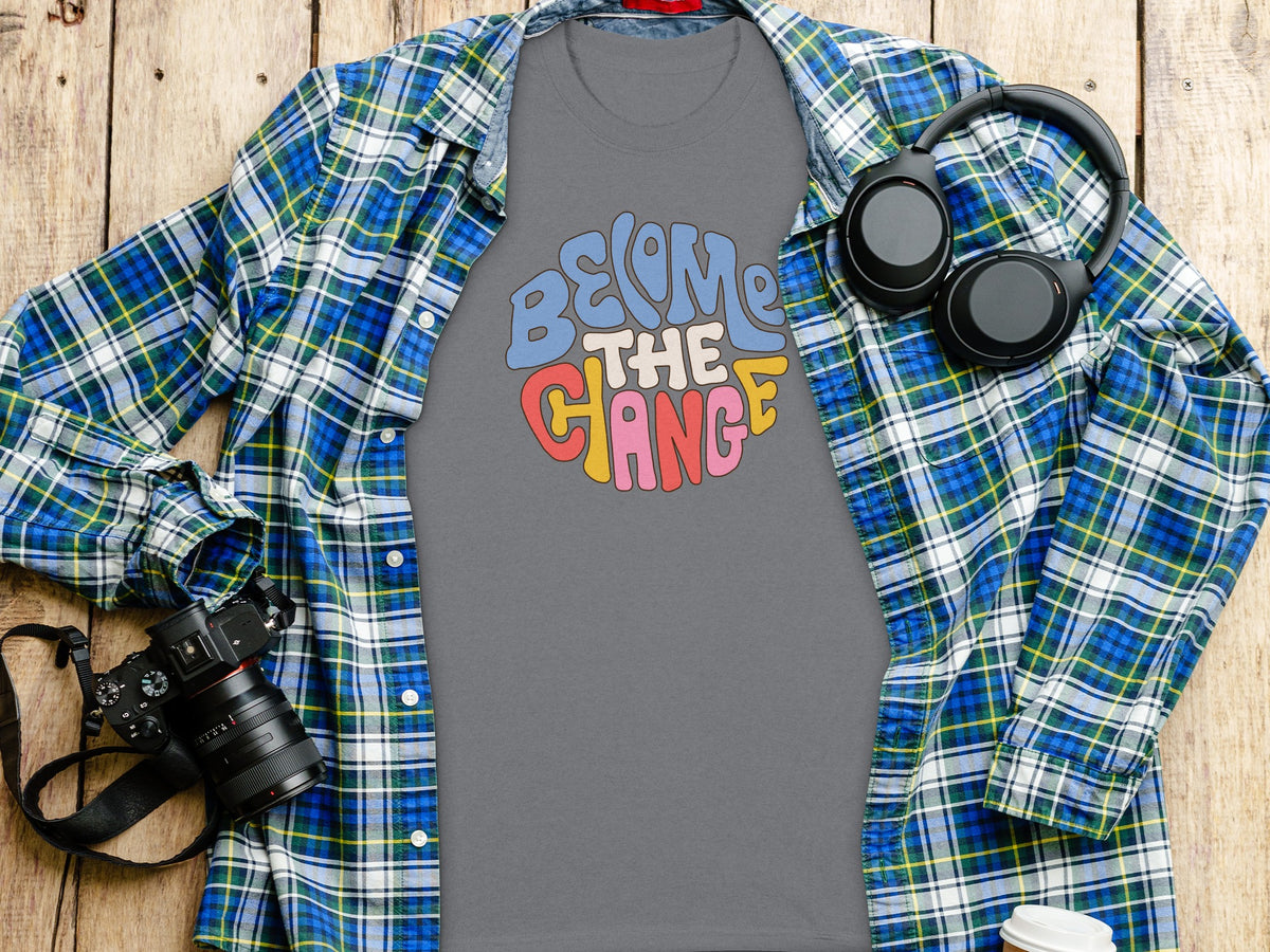 T-shirt with "Become the Change" graphic, plaid shirt, headphones, and camera.