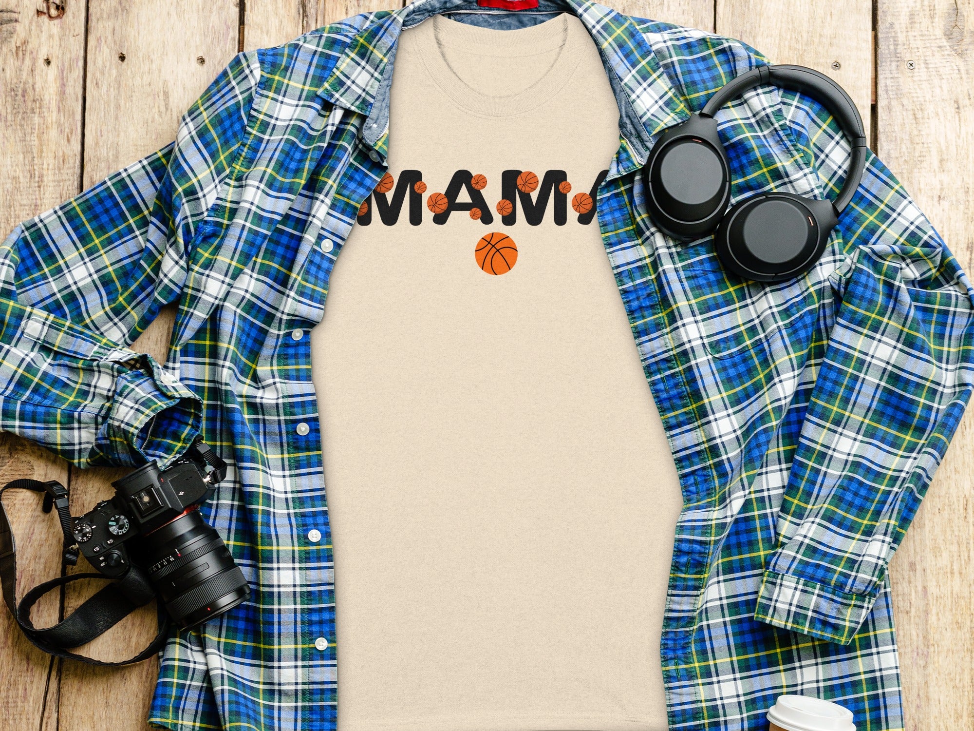 Tan t-shirt with "Mama" text and basketballs, open blue plaid shirt, headphones, and camera.