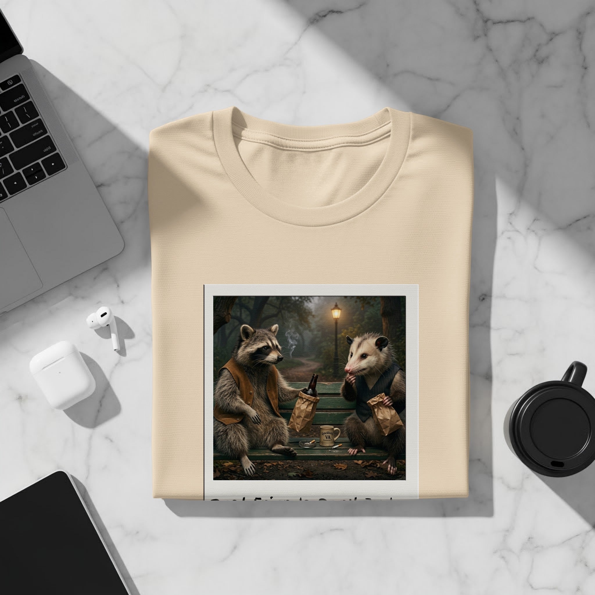 Cream t-shirt featuring a raccoon and possum sitting on a bench with brown paper bags.