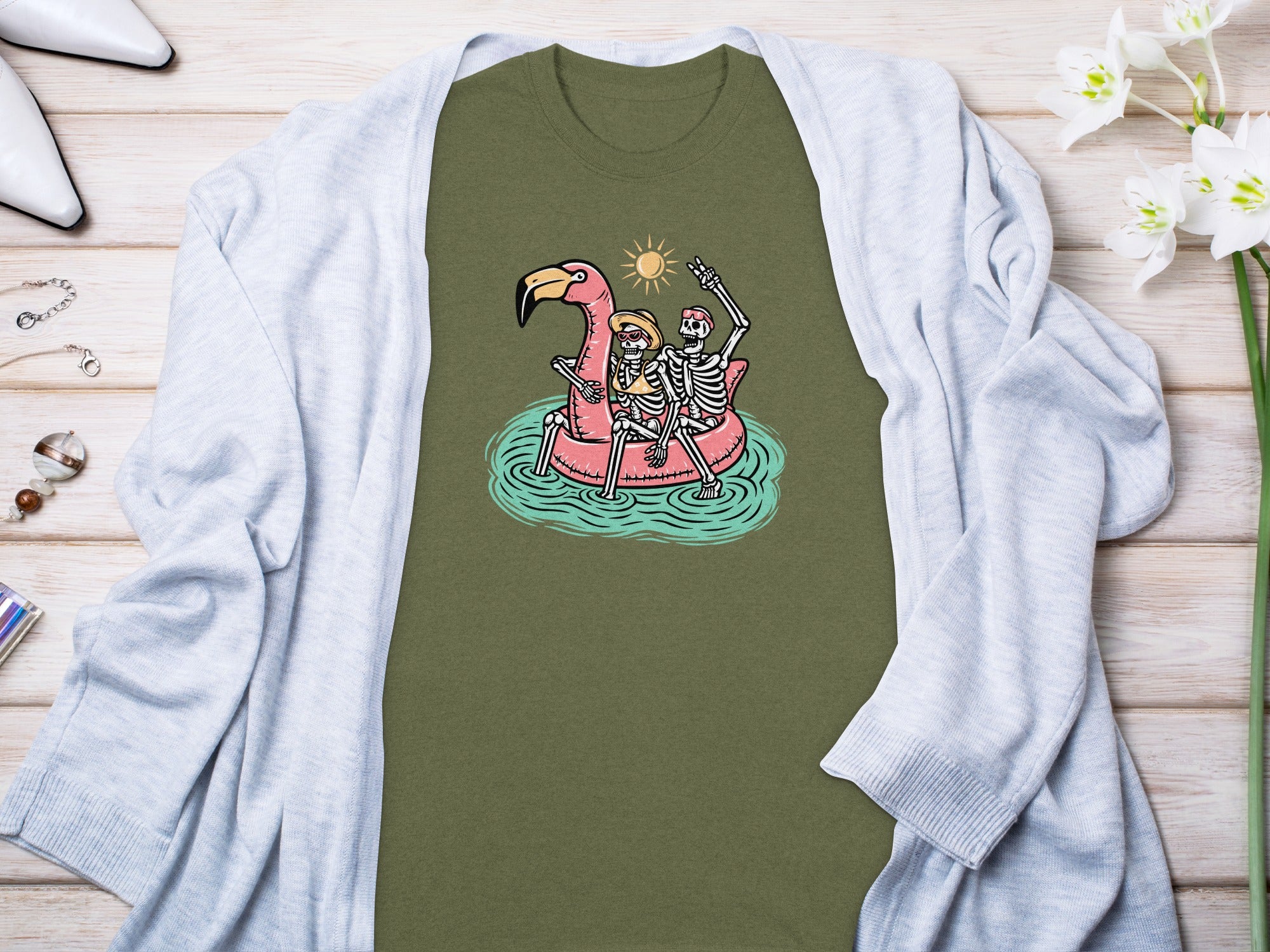 Skeleton couple on a flamingo float with sun and water graphic on a green t-shirt.