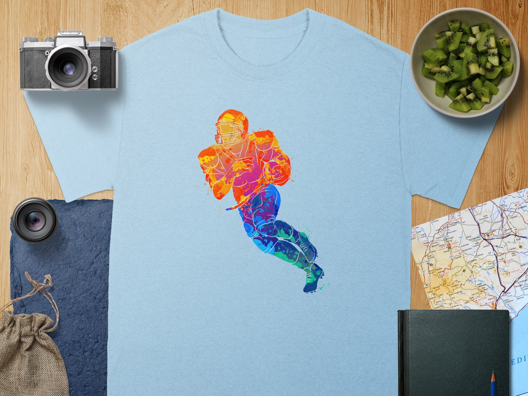 Light blue t-shirt with a colorful watercolor football player graphic.